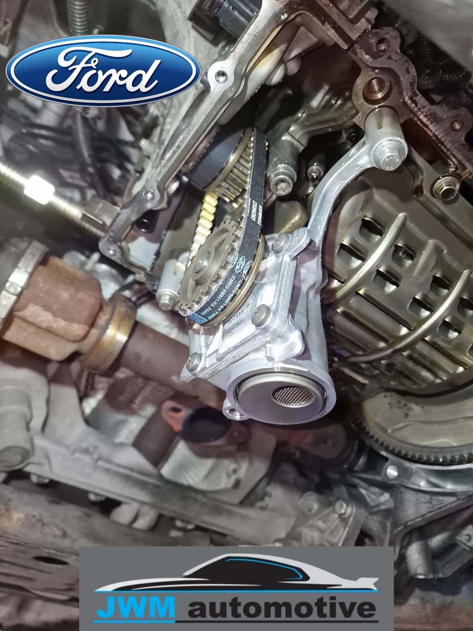Close-up view of a car engine with timing chain and metal components, partially disassembled.