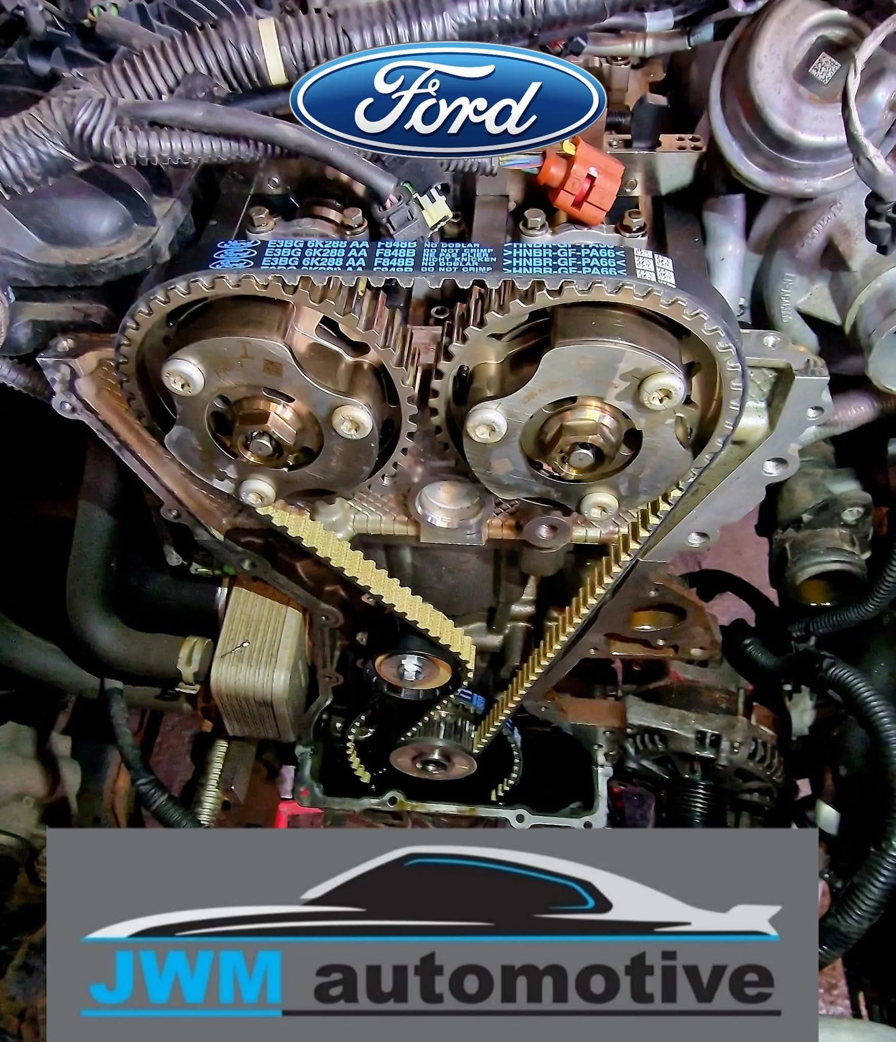 Close-up view of an automobile engine with visible timing gears, belts, and various engine components, overlaid with a graphic logo of JWM Automotive.