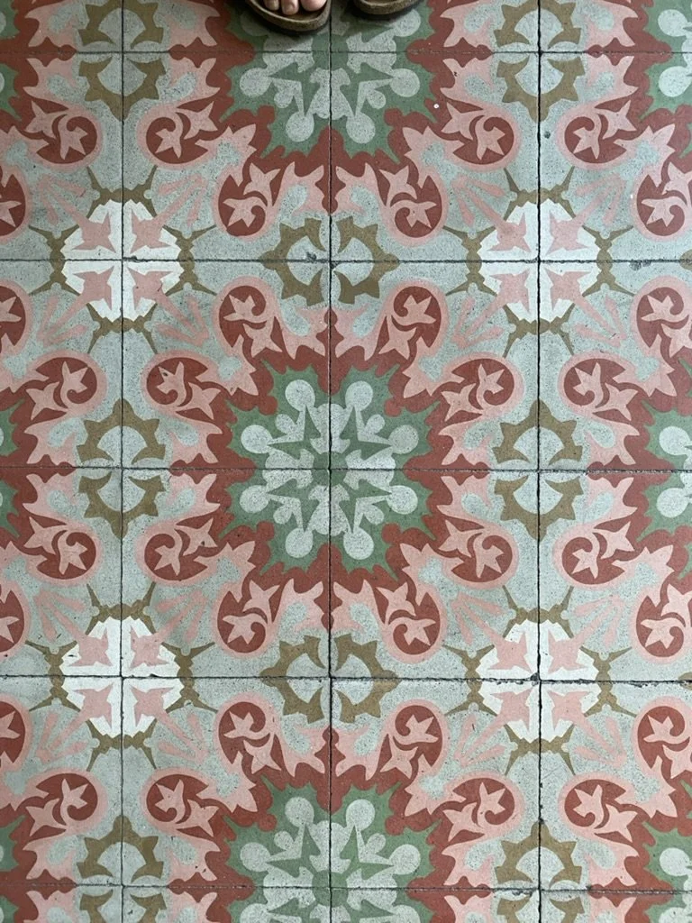 Azulejos decorativos con patrones florales en tonos rosa, verde y beige.