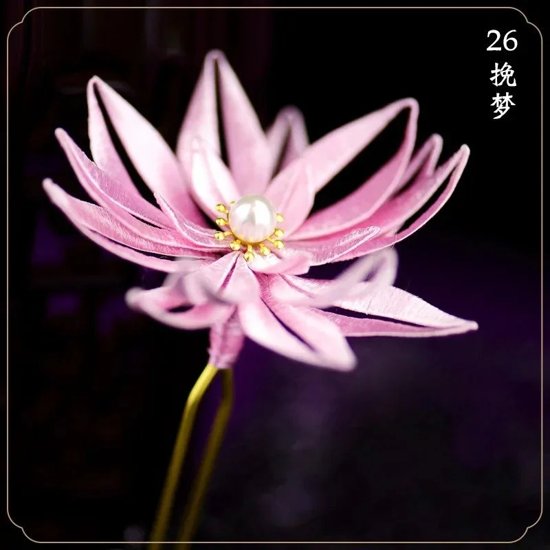 Close-up of a pink artificial flower with a pearl in the center, against a dark background.