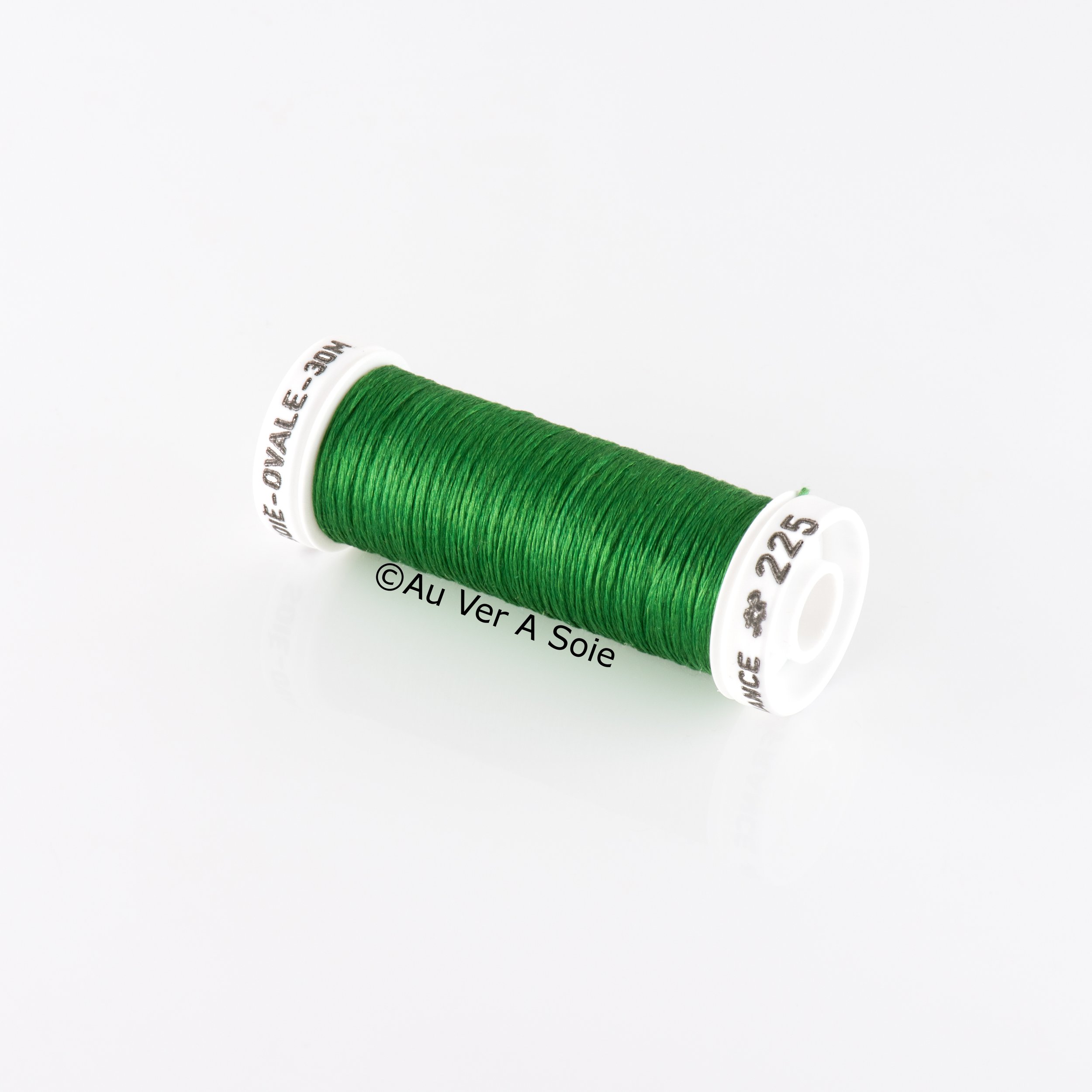 A spool of green thread on a white background.