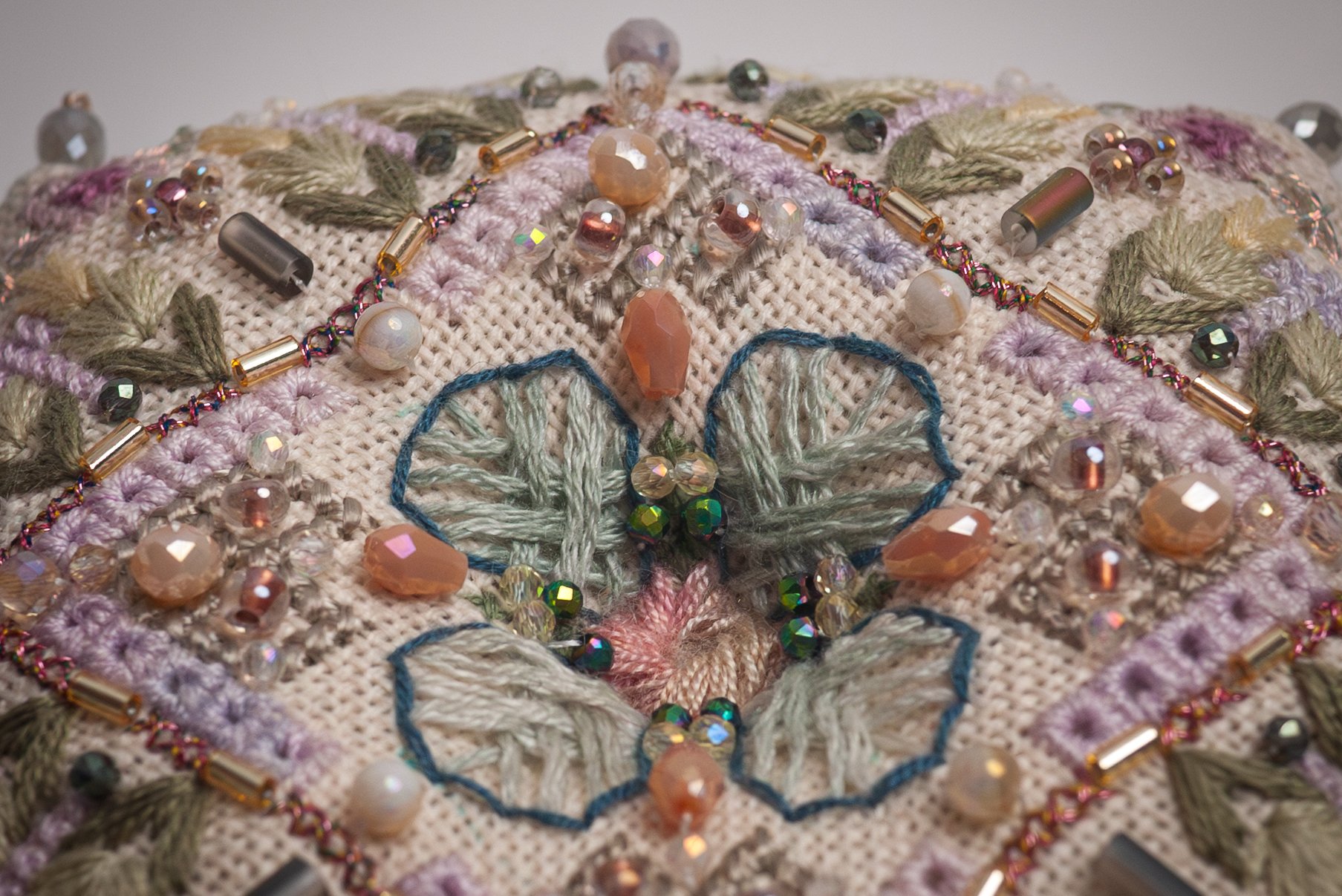 Close-up of embroidered fabric decorated with beads, sequins, and colorful thread.
