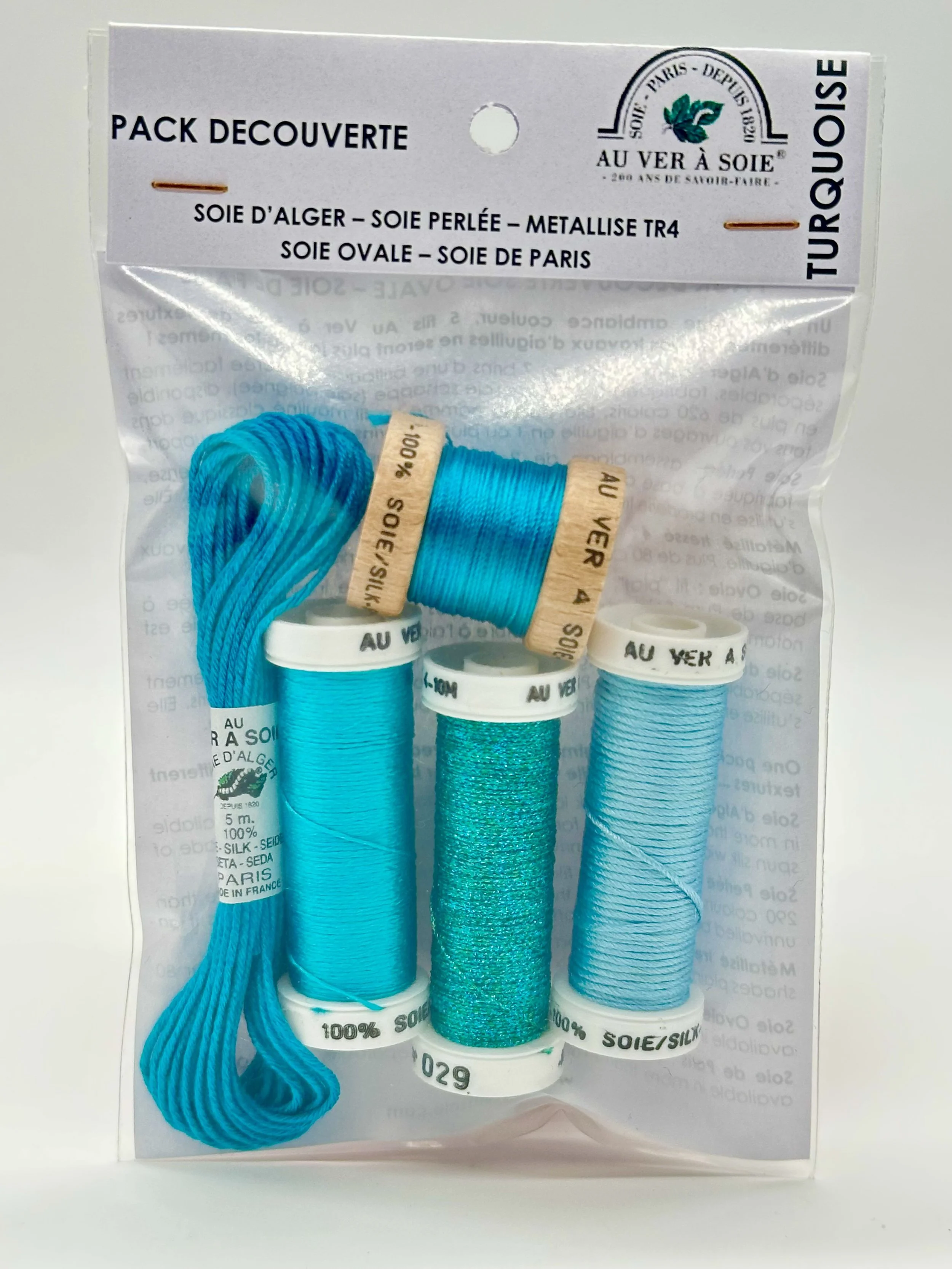A sealed package of blue sewing threads with four spools of different shades of blue thread visible.