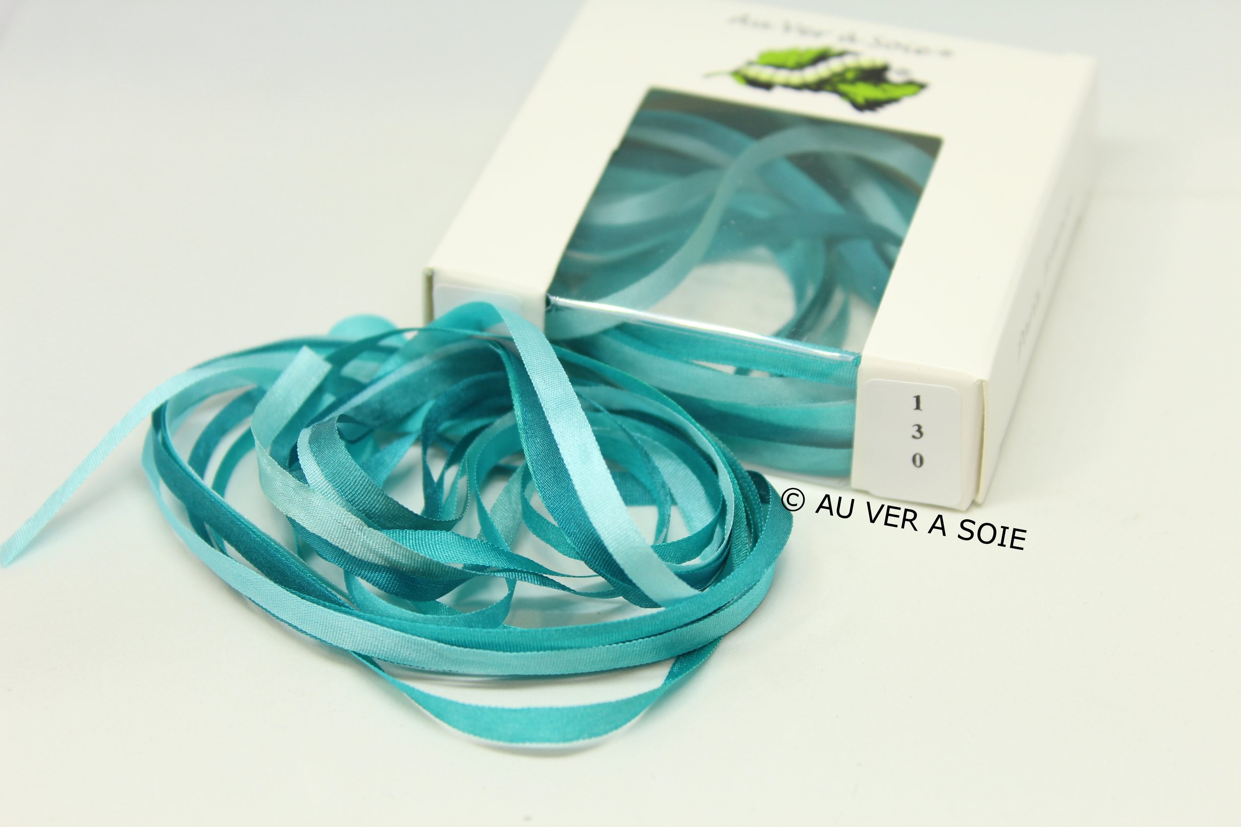 Close-up of a box of teal and white satin ribbons with a window showing the ribbons inside.