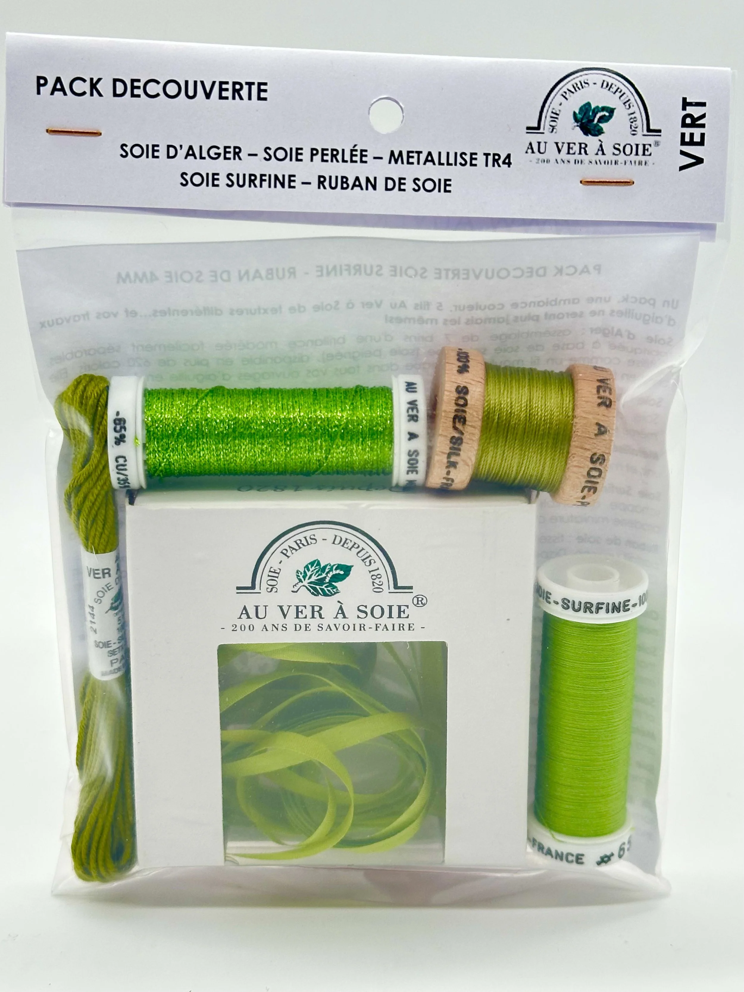 A package containing green sewing threads and a label with French text and a green leaf logo.