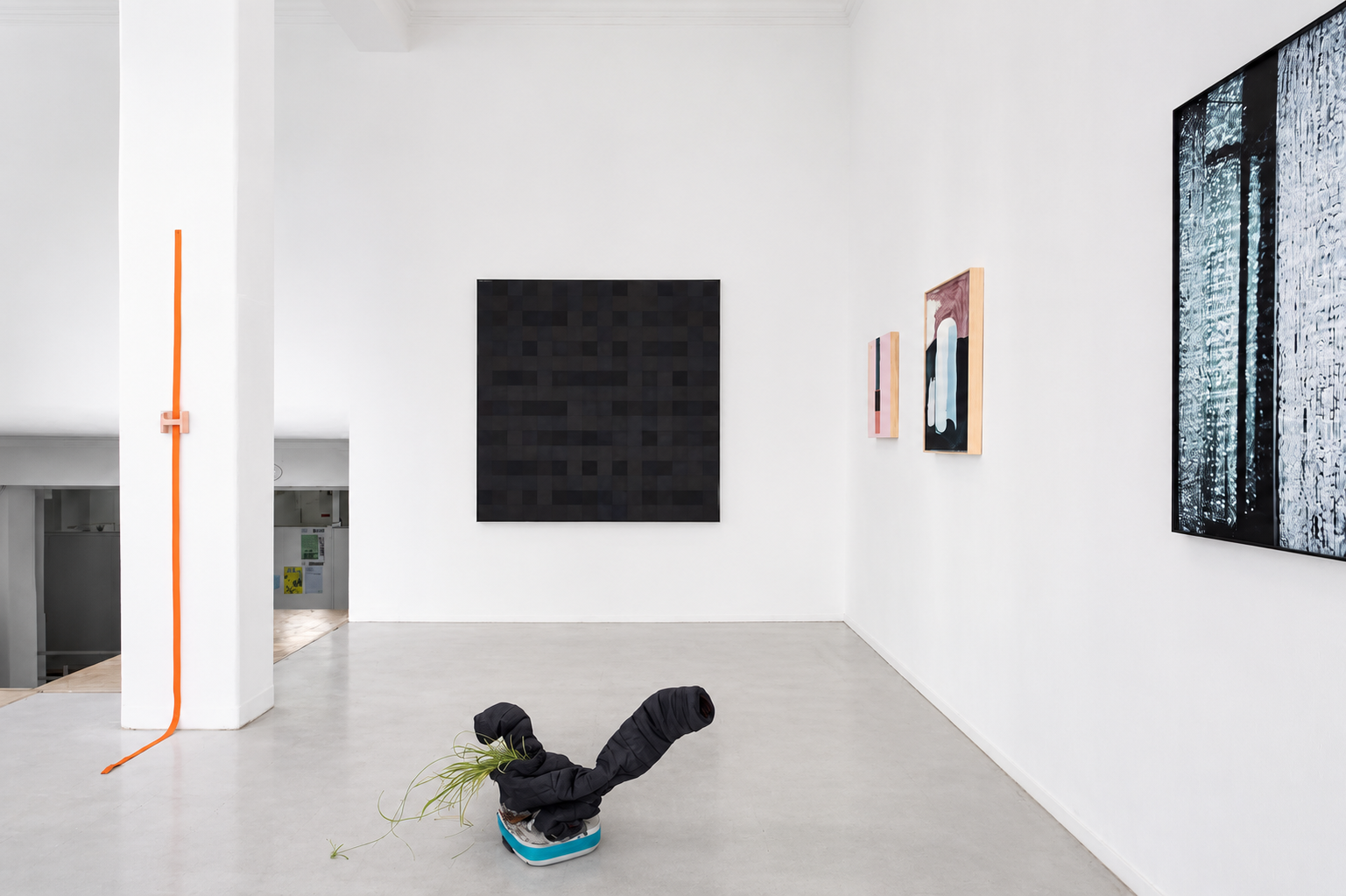 Modern art gallery with abstract paintings on white walls and a sculpture with fabric and plants on the floor.
