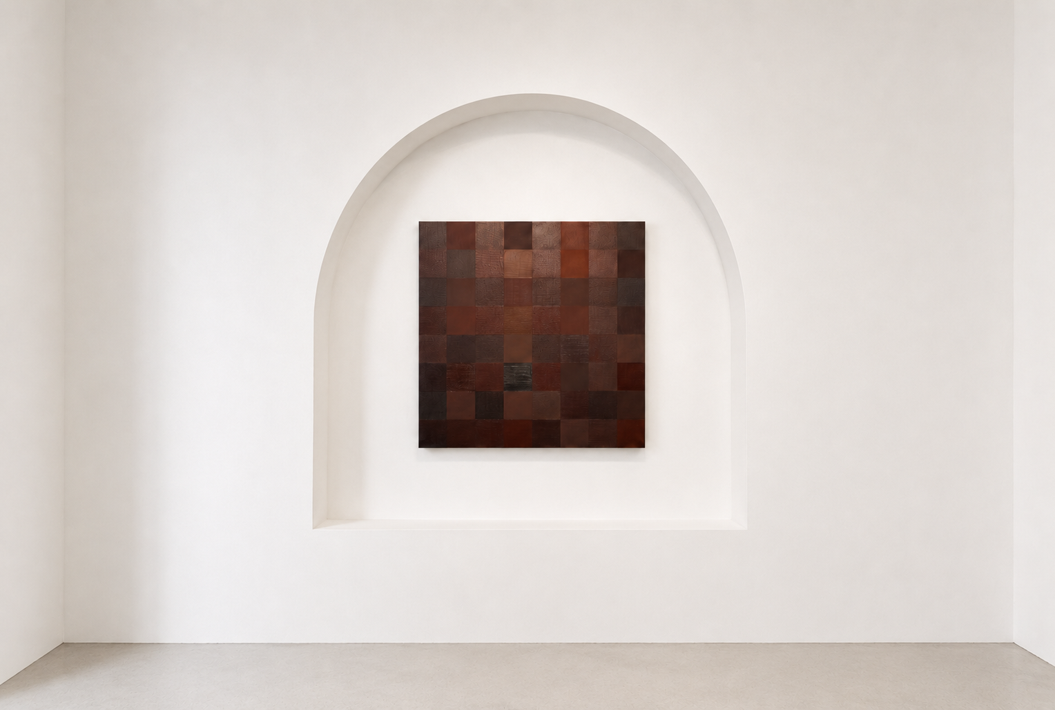 A square wall art piece with a grid of small wooden squares in various shades of brown, mounted in a recessed arch alcove on a white wall.