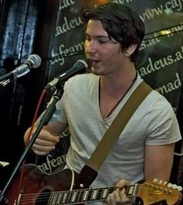 Junger Mann singt und spielt Gitarre bei einer Live-Performance