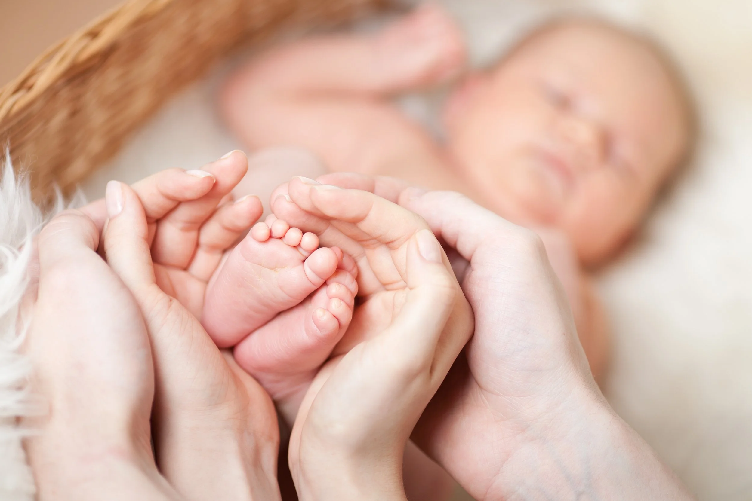 Une maintenant un bébé avec ses mains, en arrière-plan flou d'une femme.