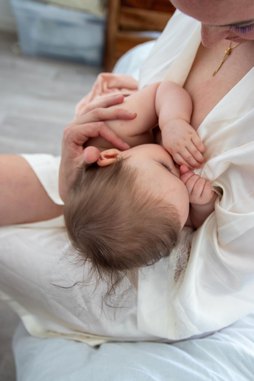 Une mère allaite son bébé en position physiologique, l'enfant repose contre elle, partageant un moment d'intimité et de tendresse.