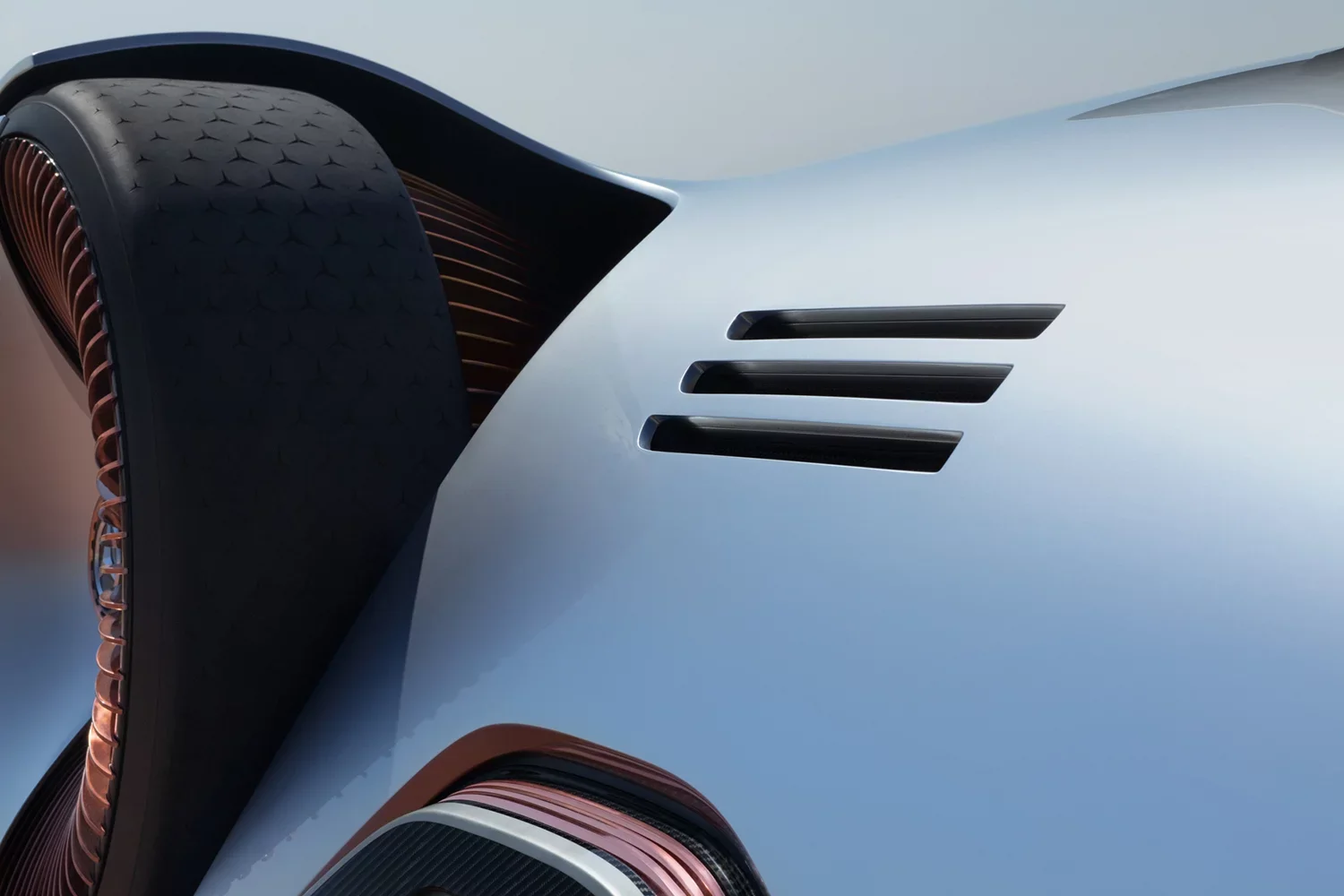 Close-up of a futuristic car's front section showing a metallic silver body, black vents, and copper-colored accents.