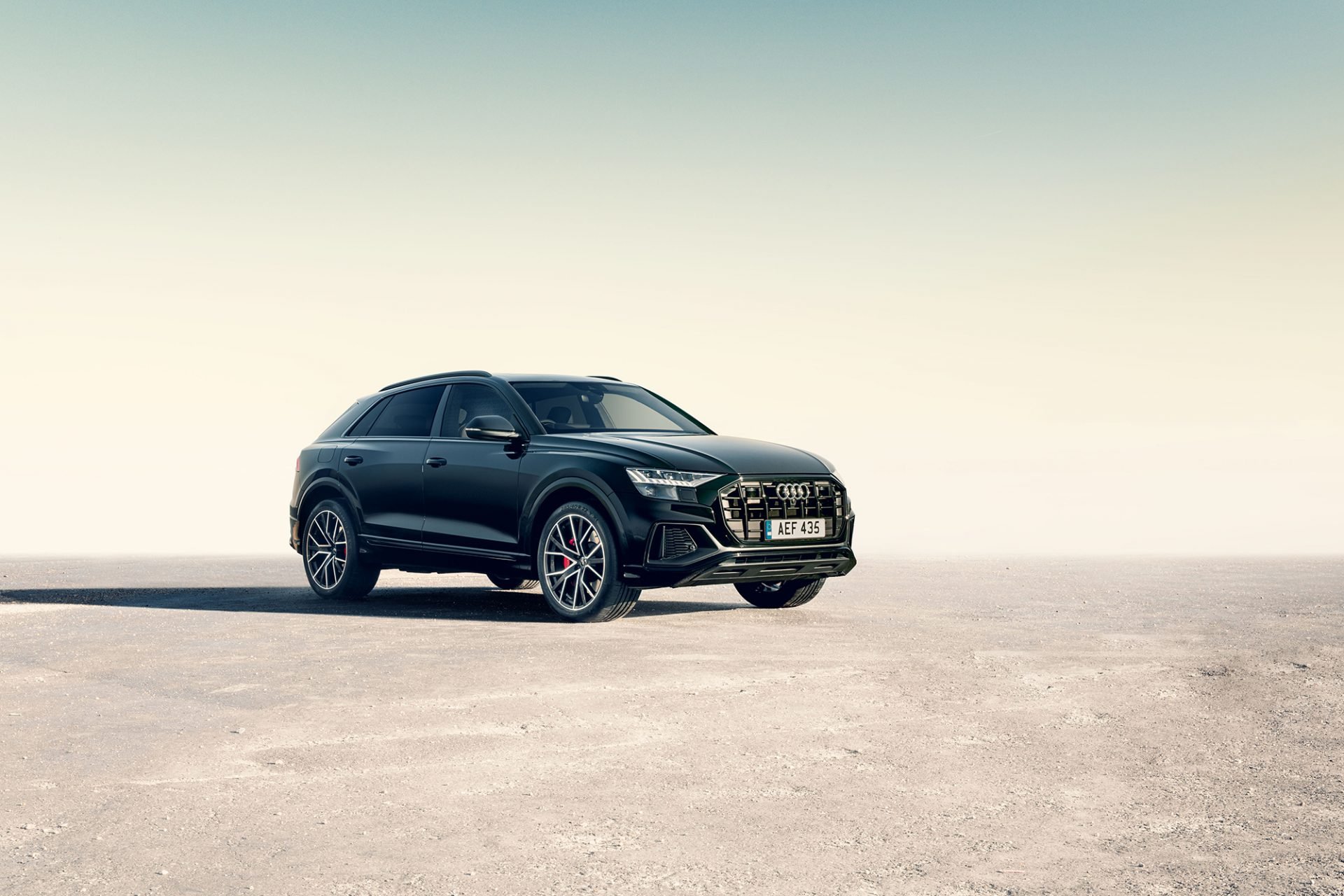 A black Audi SUV parked on a flat, open surface with a clear sky in the background.