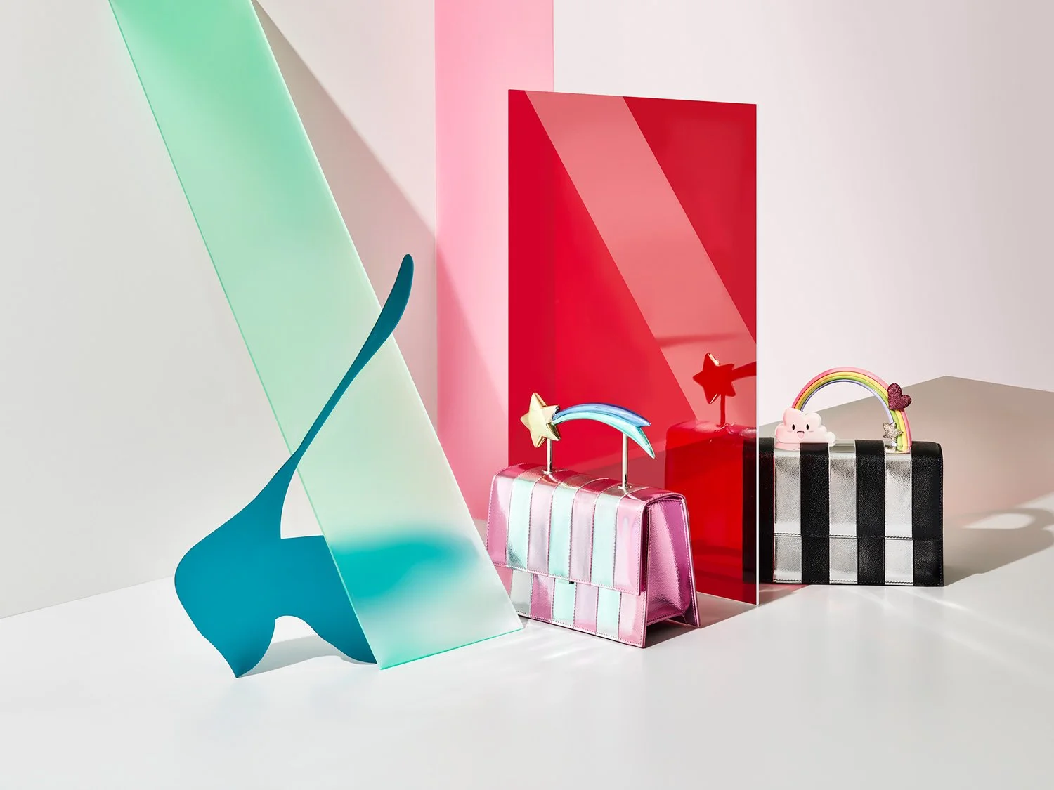 Two colorful handbags with rainbow and star decorations, set against pink, red, and green geometric backgrounds.
