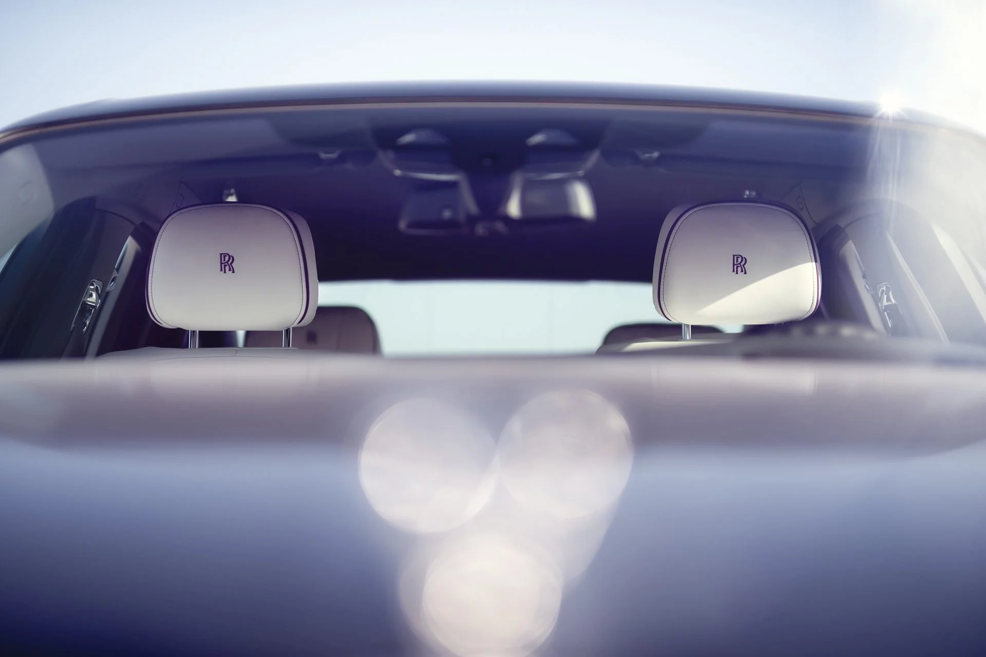 Front view of a luxury car showing white headrests with Rolls Royce logos inside the vehicle.