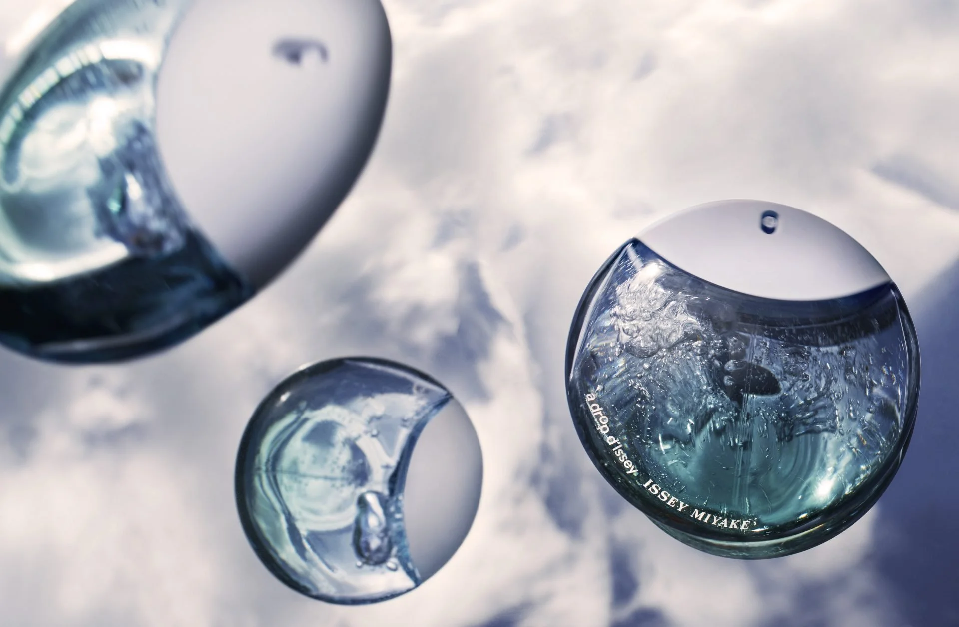 Close-up of broken glass jars with water inside, reflecting the sky with clouds.