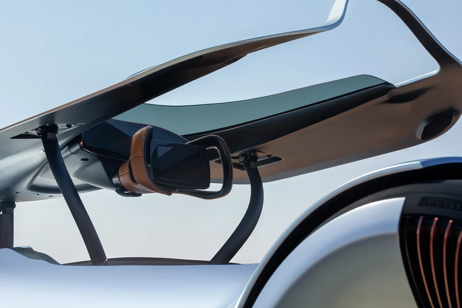 Close-up of a futuristic vehicle's aerodynamic design, with a sleek metallic surface, a tinted visor, and visible sunroof, under a clear blue sky.