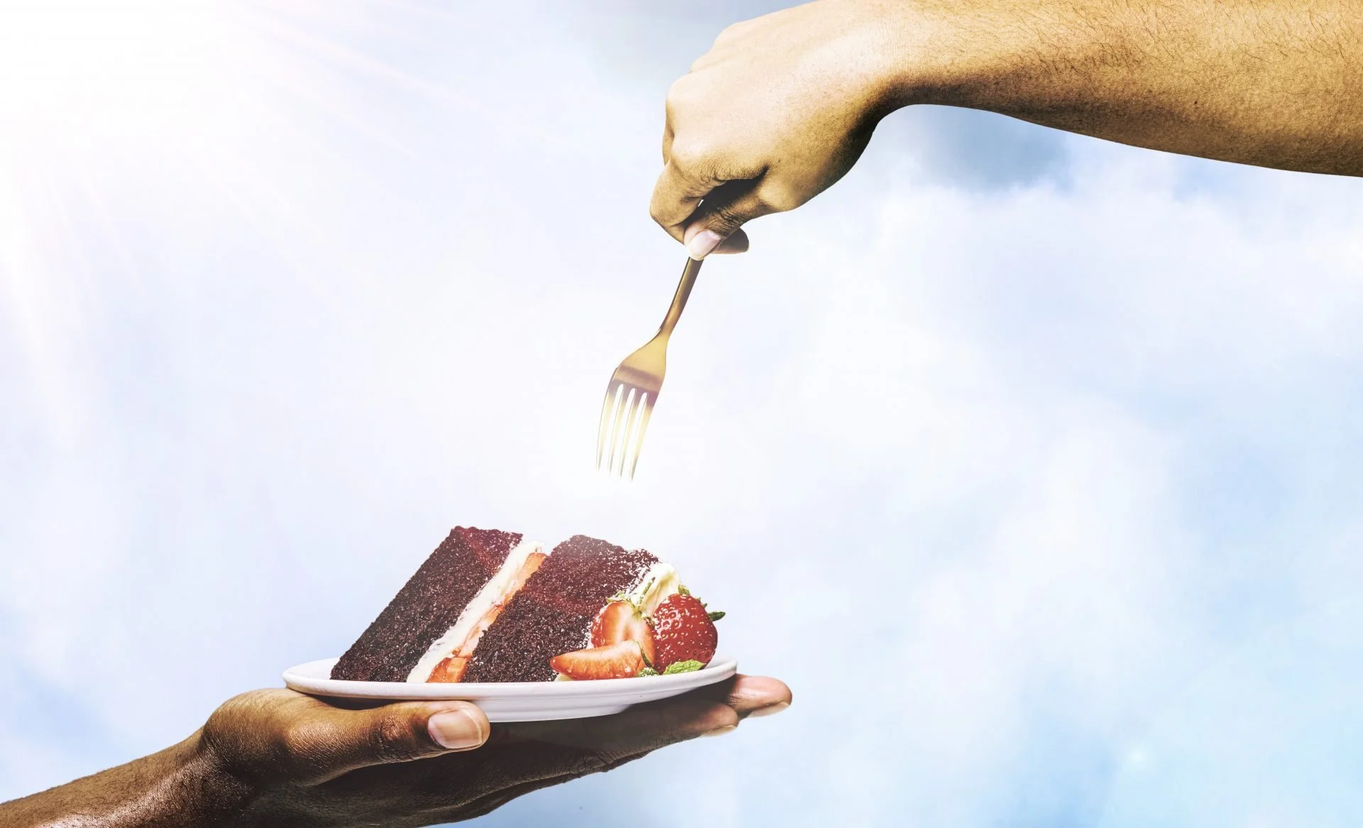 A person's hand holding a white plate with a slice of chocolate cake topped with strawberries, while a hand to the right uses a fork to lift a piece of the cake. The background shows a cloudy sky.