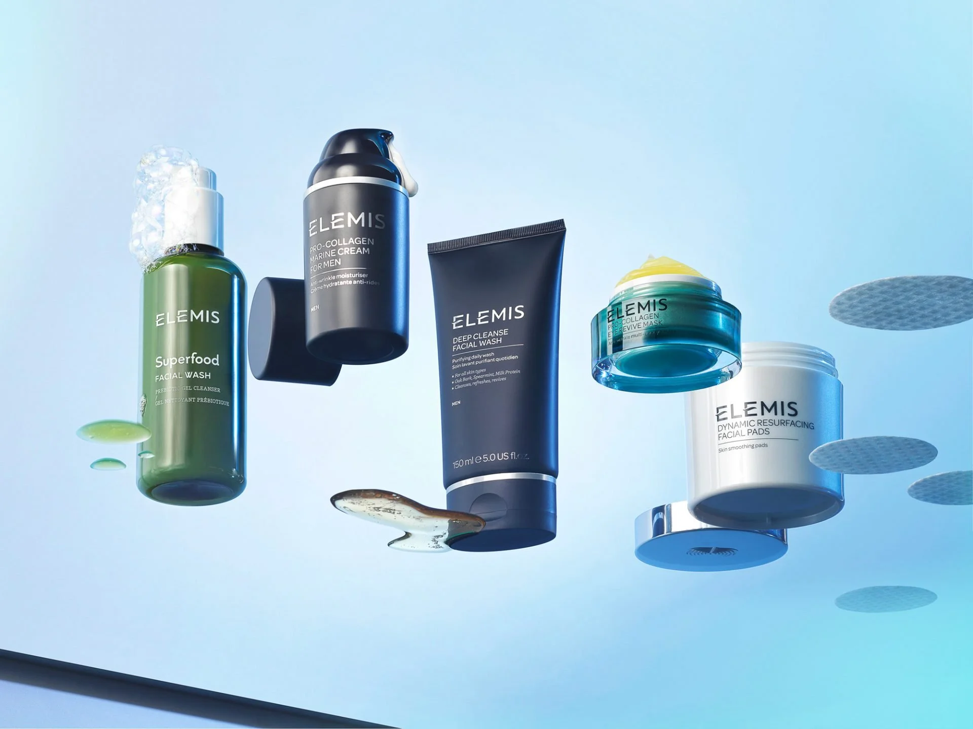 Arrangement of Elemis skincare products on a light blue background with floating gel and cream splashes.