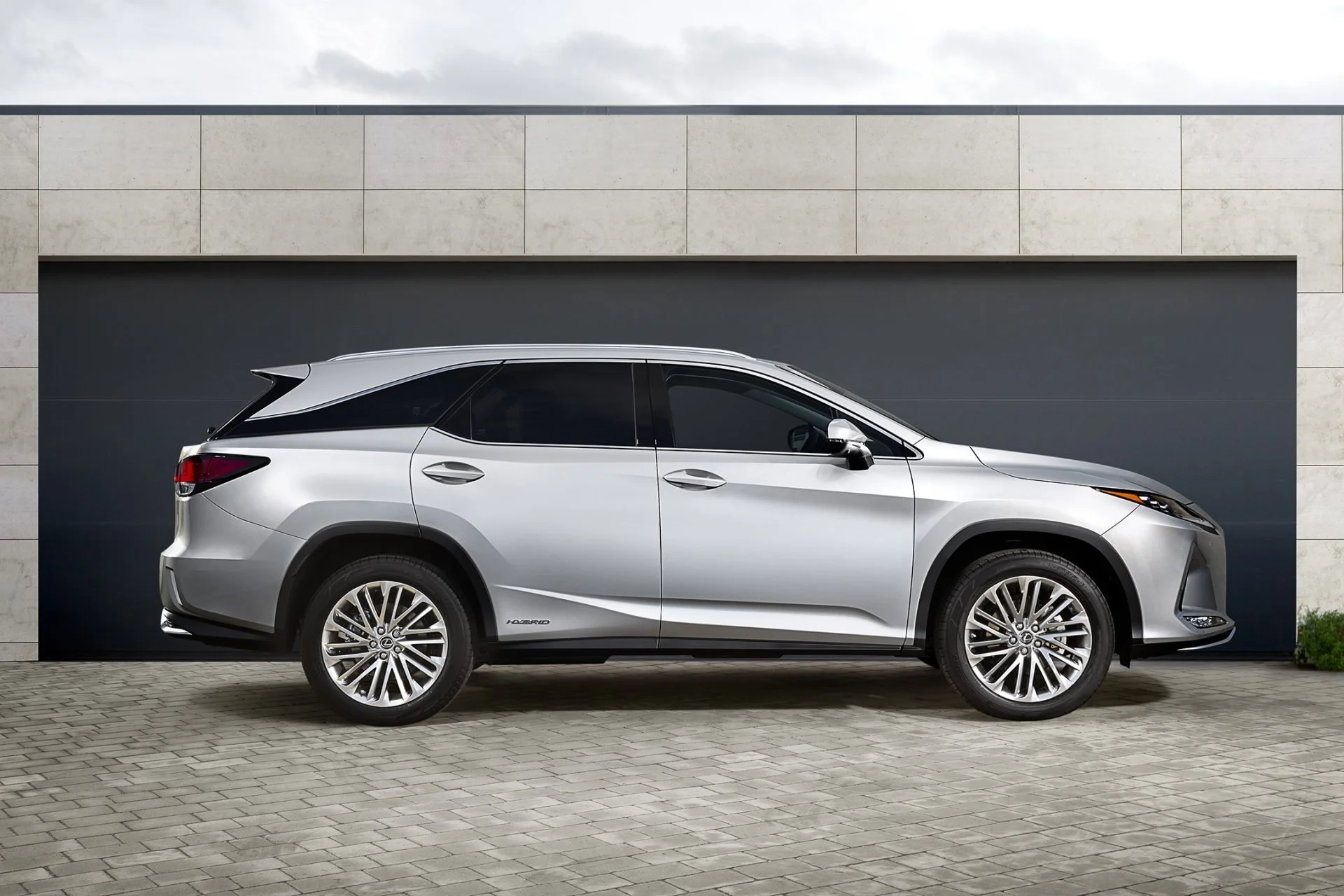 A silver SUV parked in front of a modern building with a gray garage door and beige stone walls.