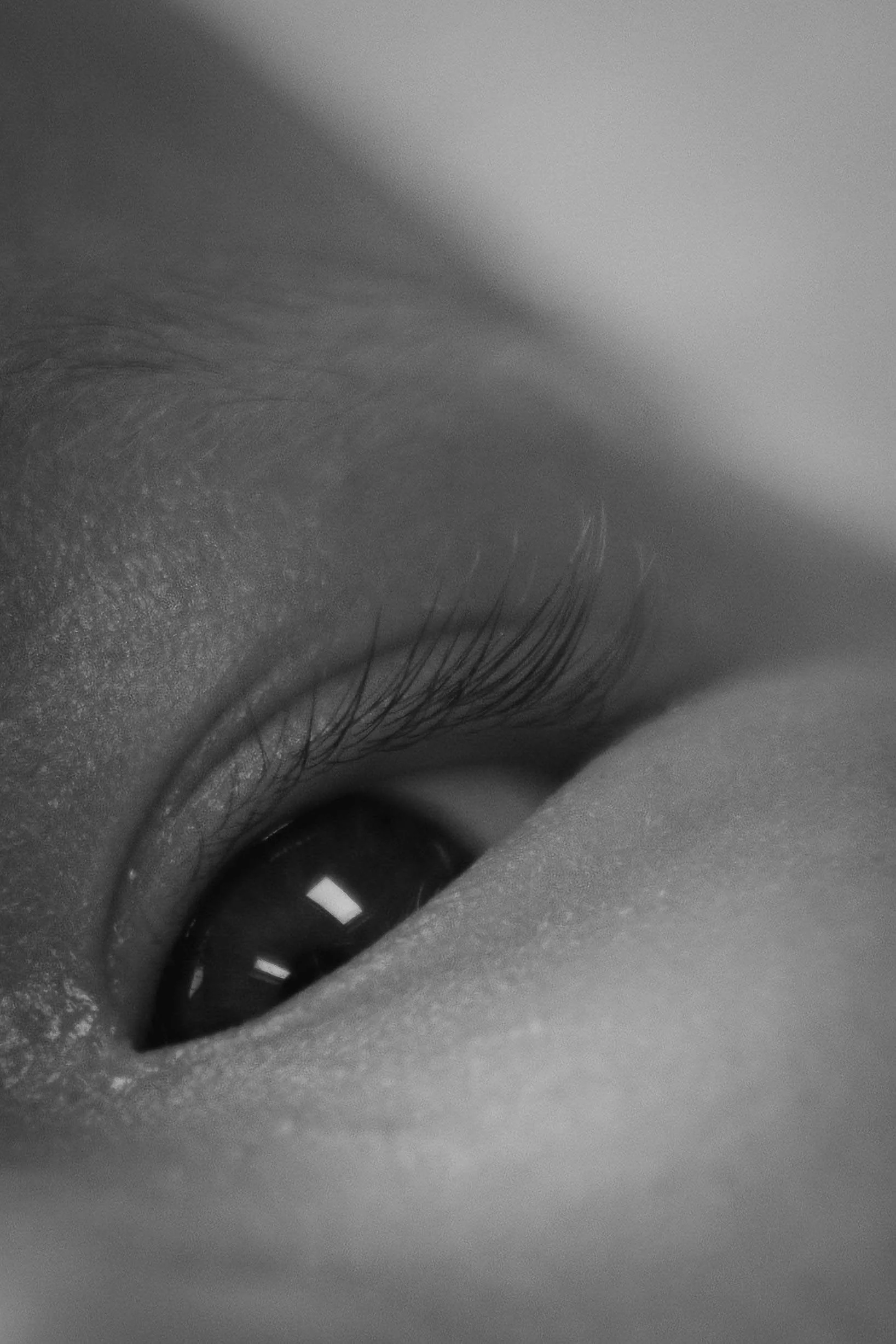 Close-up of a person's eye with long eyelashes. The image is black and white.