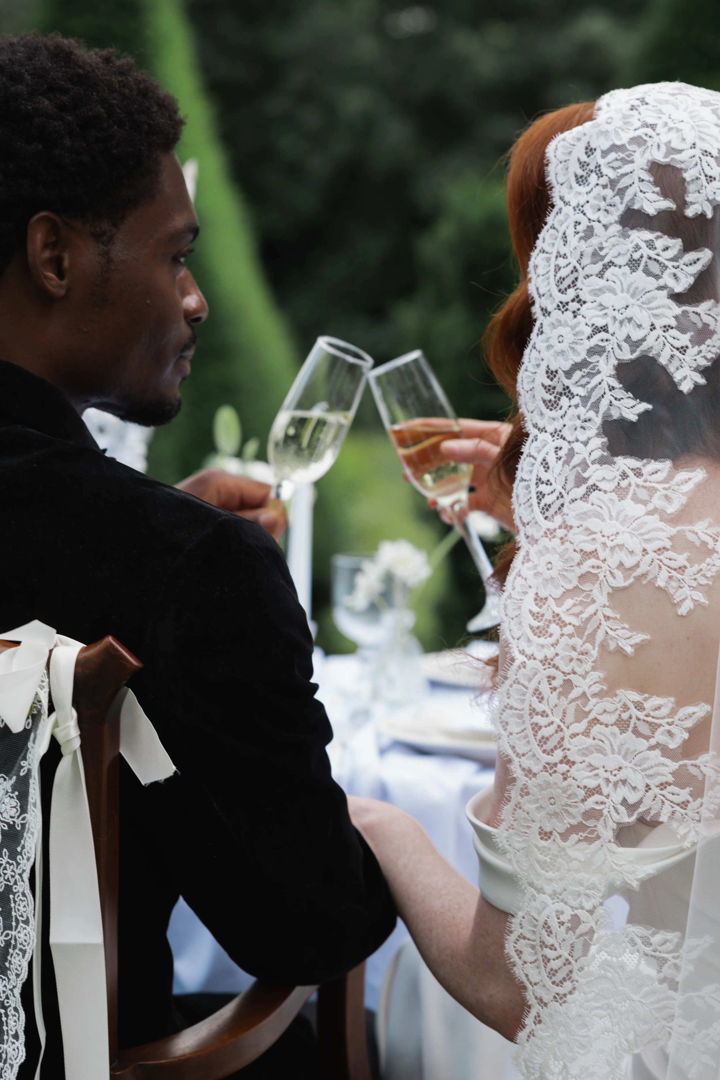 A couple dressed in wedding attire sharing a toast with champagne at their wedding reception.