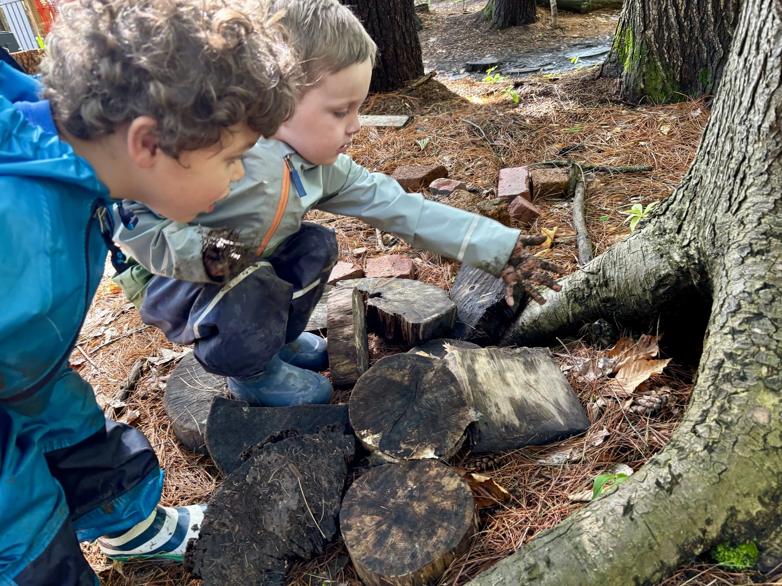 Two children exploring the woods during a nature-based pediatric occupational therapy group.