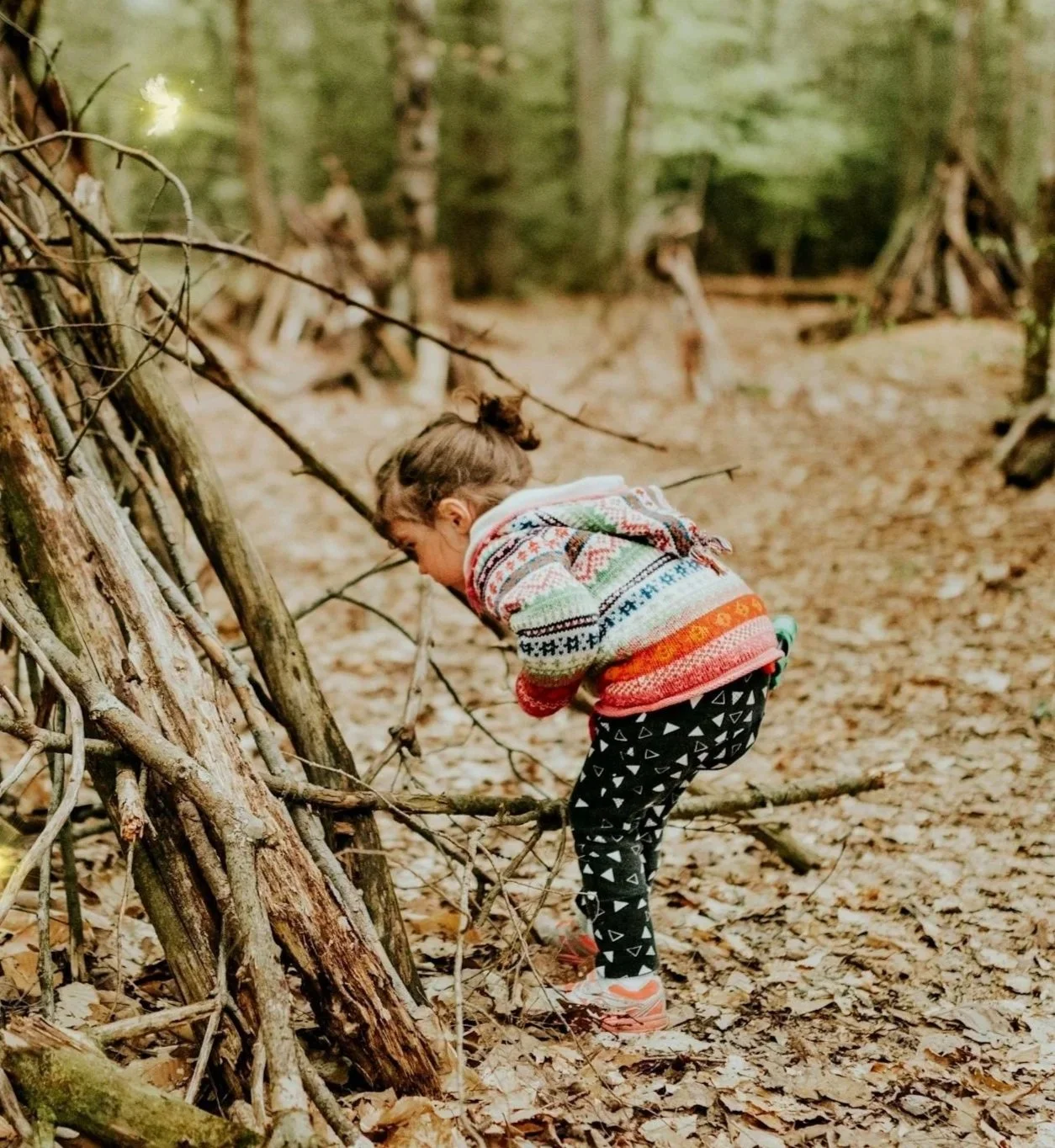Child exploring a nature fort through imaginative outdoor play.