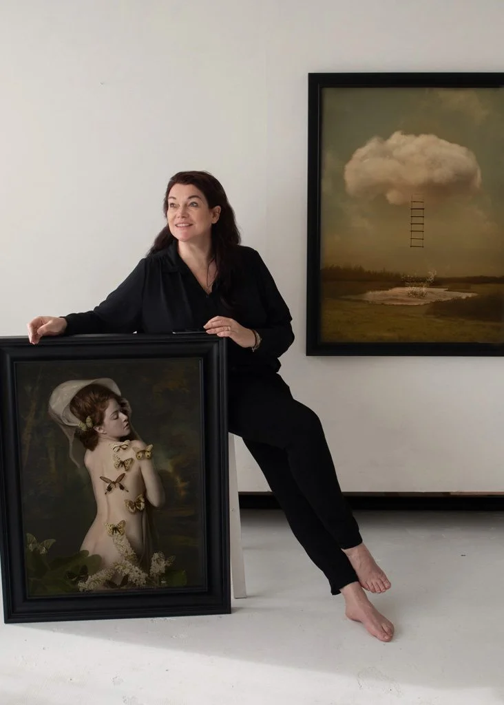 Een vrouw in een zwart shirt en zwarte broek zit op haar benen, met haar linkerarm op een gesitueerd schilderij. Ze staat naast twee kunstwerken: een grote lijst met een schilderij van een meisje dat bedekt is met gouden vlinders en een schulprijk dat een regenwolk boven een landschap afbeeldt.