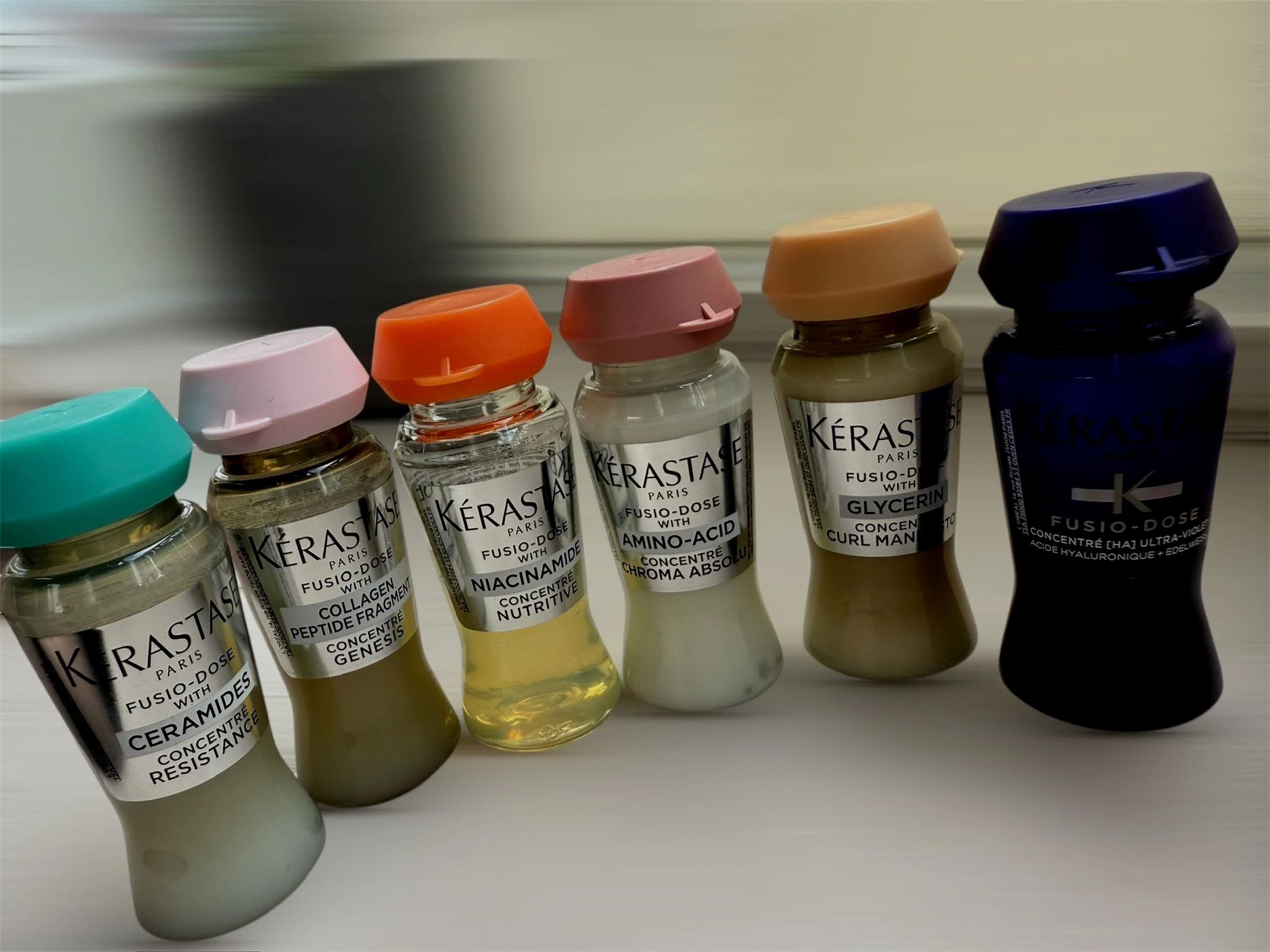 Collection of colorful Kérastase hair treatment serums and small vials with labels.