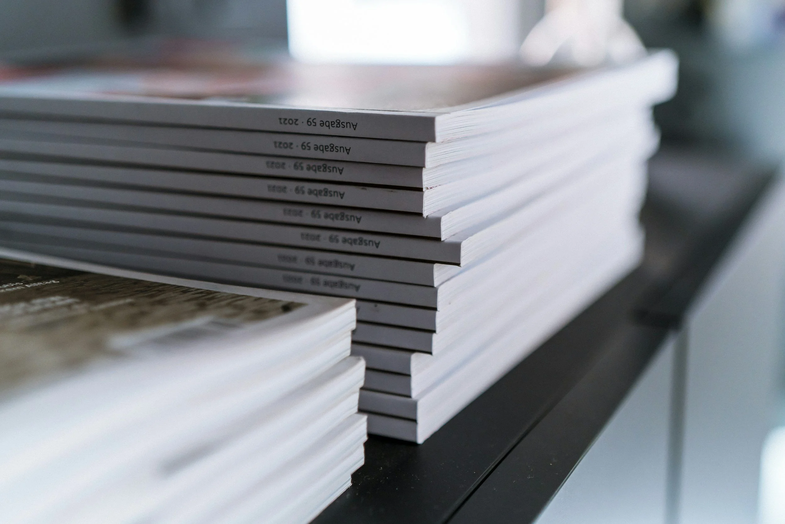Stacked white catalogues or brochures on a dark surface.