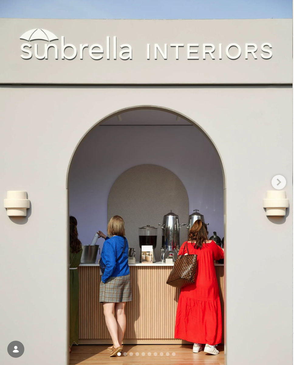 People buying coffee at a counter inside a store called 'Sunrella Interiors' with a canopy-shaped logo.