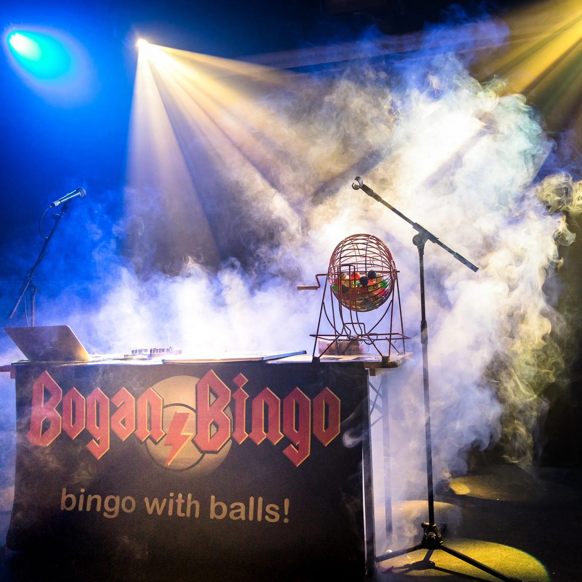 Stage with colorful lighting, smoke effects, a microphone, a wire bingo cage filled with colored balls, and a sign that reads 'bingo with balls'.