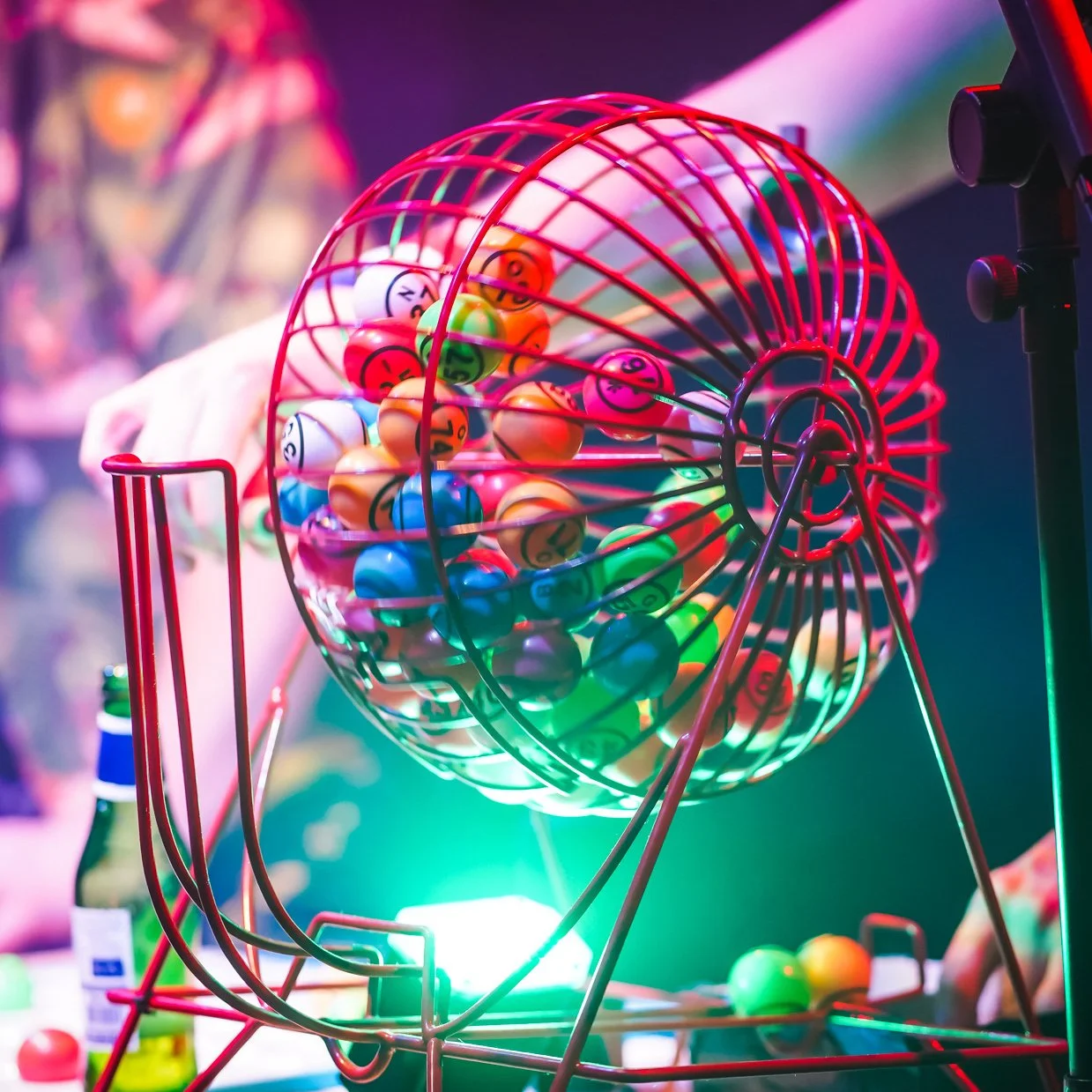 Colorful bingo balls inside a red metal cage at a bingo game event.