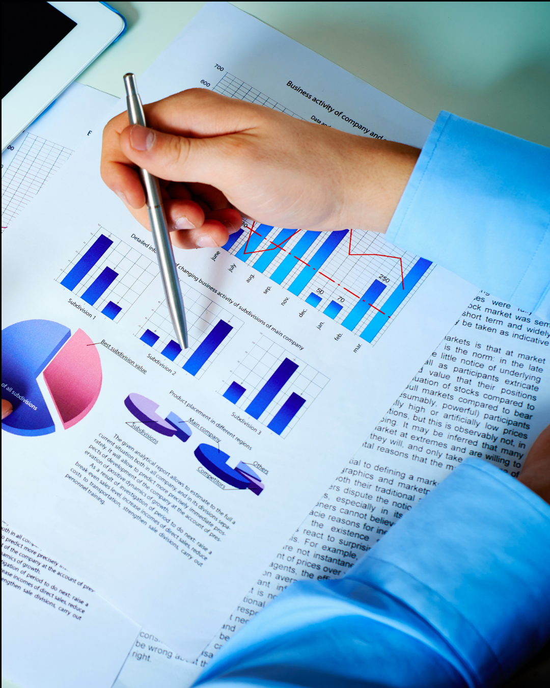 A person's hand holding a silver pen over functional nutrition test with bar graphs, pie charts, and line graphs on a desk.