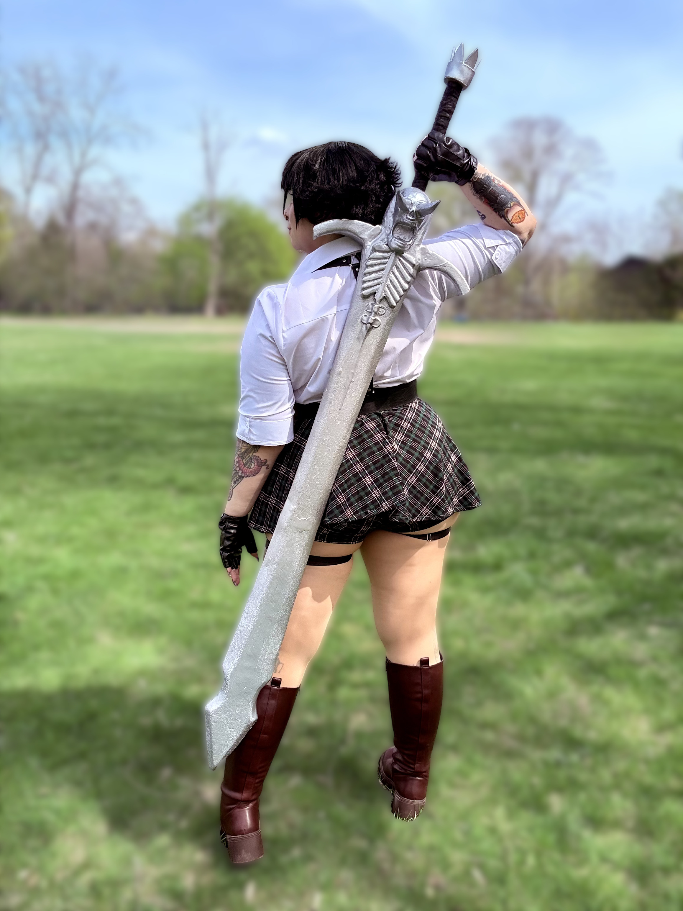 Woman facing away from the camera in cosplay holding a large sword.