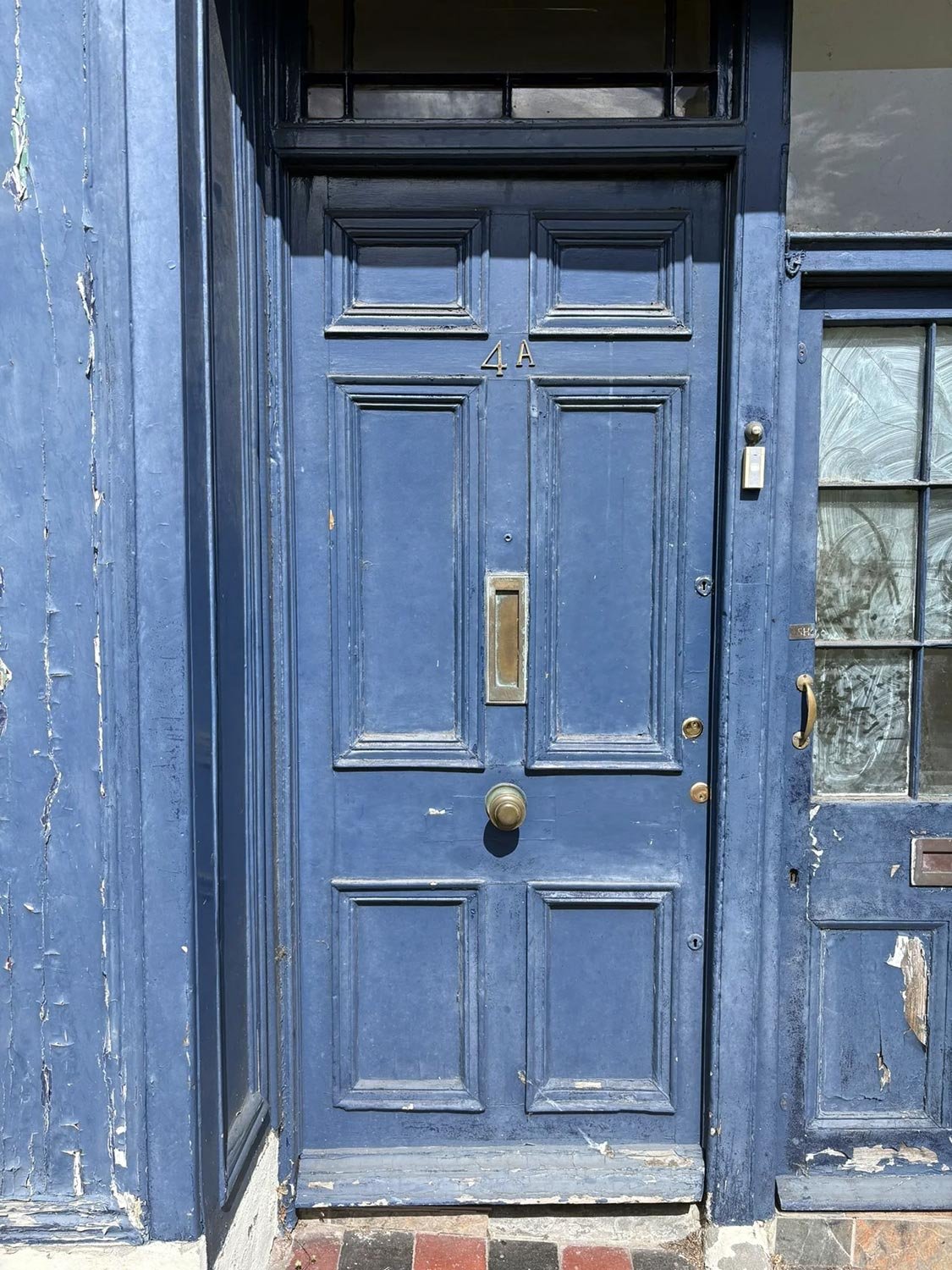 A doorway with flaked blue paint and blue panelled door with number 4A. The building was part of a heritage project for Heritage Storeys.