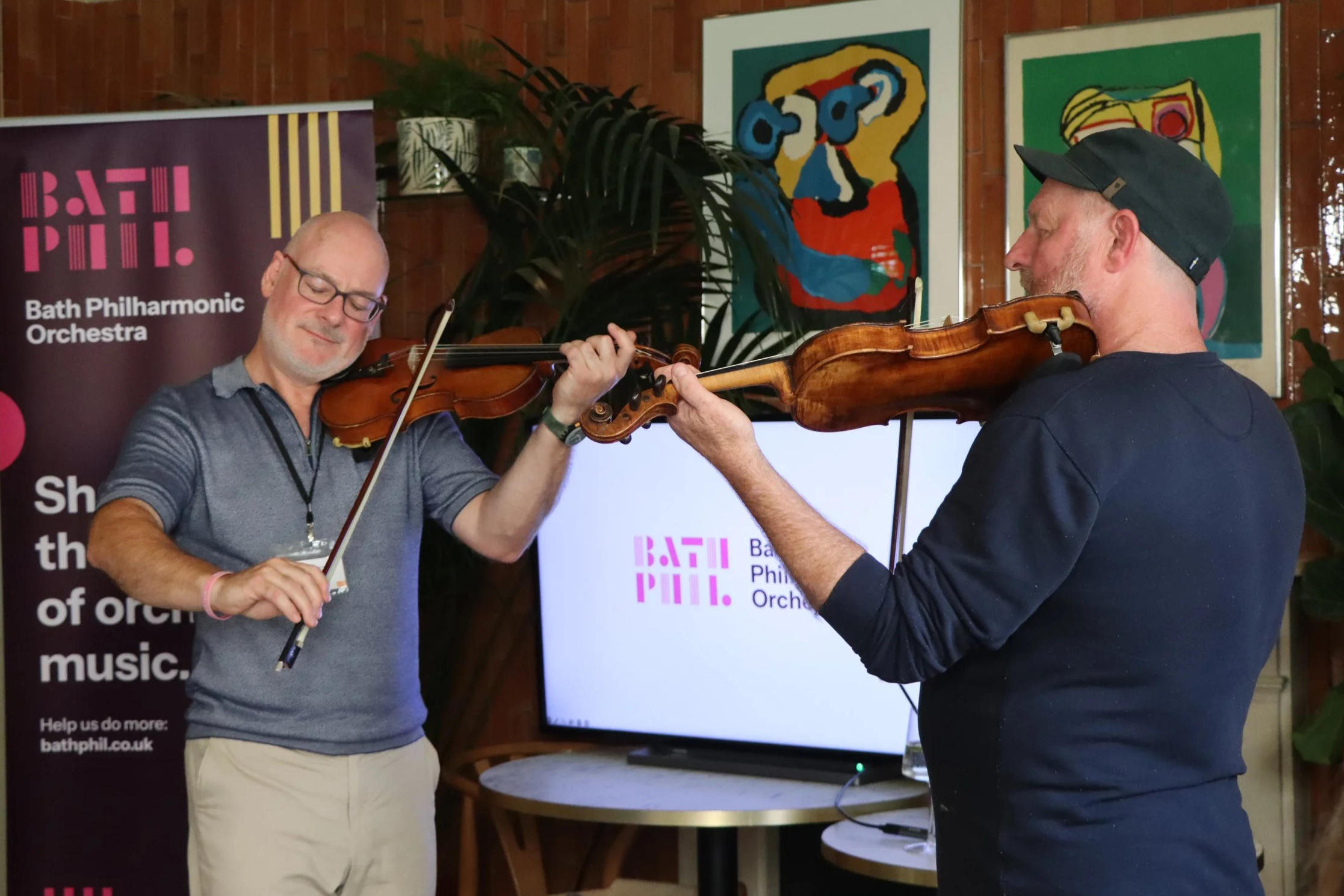 Two violinists perform at Bath Philharmonic Orchestras brand reveal party.