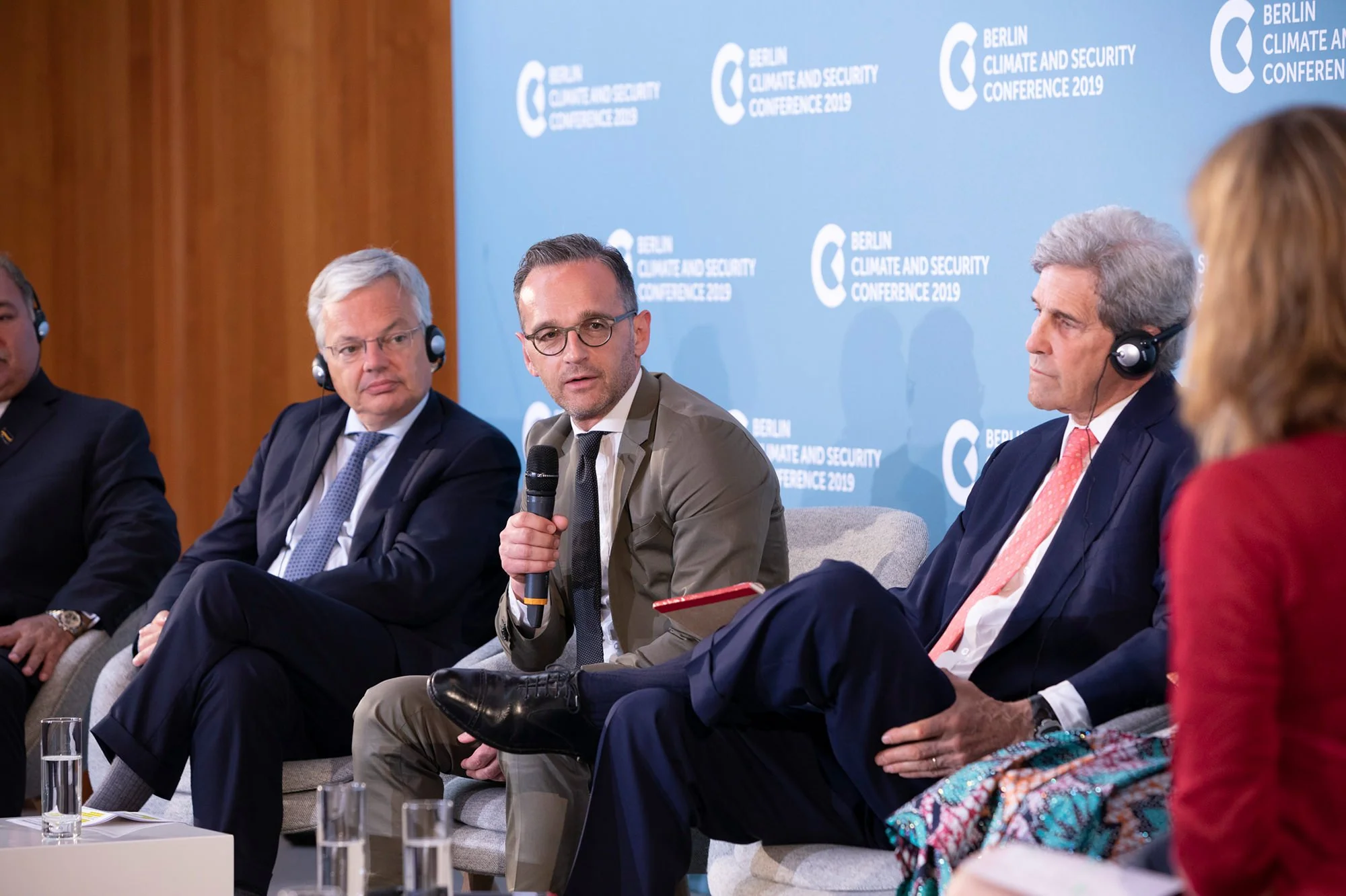 Menschen bei einer Konferenz zum Thema Umwelt und Sicherheit in Berlin 2019, Heiko Maas, Außenminister der BRD, spricht ins Mikrofon, im Hintergrund ein blauer Banner mit dem Text "Berlin Climate and Security Conference 2019".