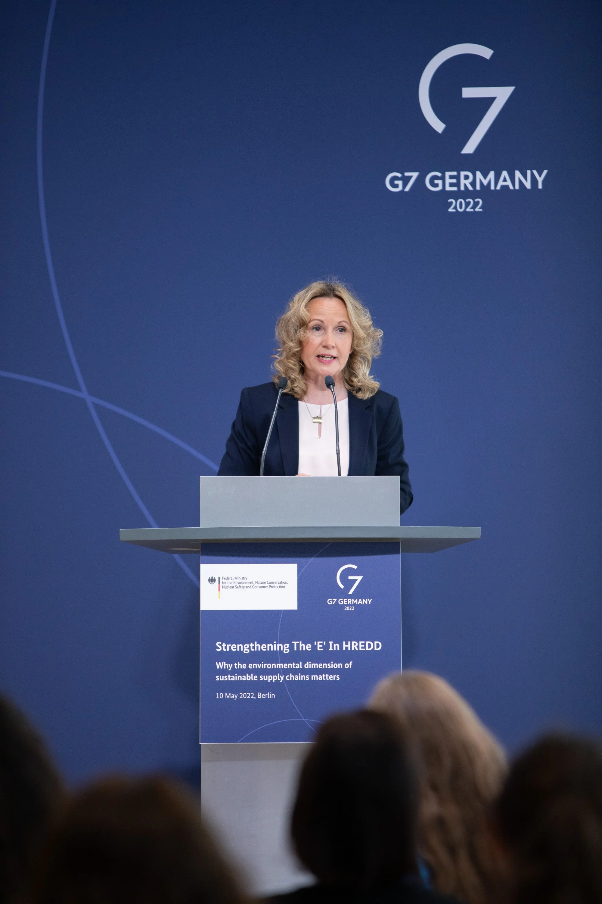 Eine Frau spricht bei einer Konferenz zum Thema nachhaltige Lieferketten, der Hintergrund zeigt das G7-Logo und den Titel der Veranstaltung in Berlin im Jahr 2022.
