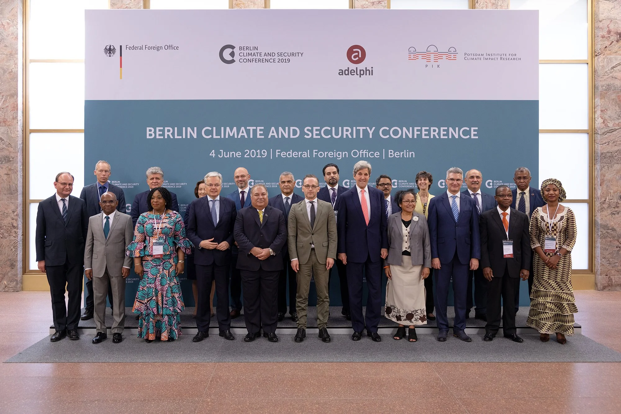 Gruppe von Menschen bei der Berlin Climate and Security Conference 2019 am 4. Juni in Berlin, vor einem blauen Hintergrund mit Konferenzinformationen und Logos.