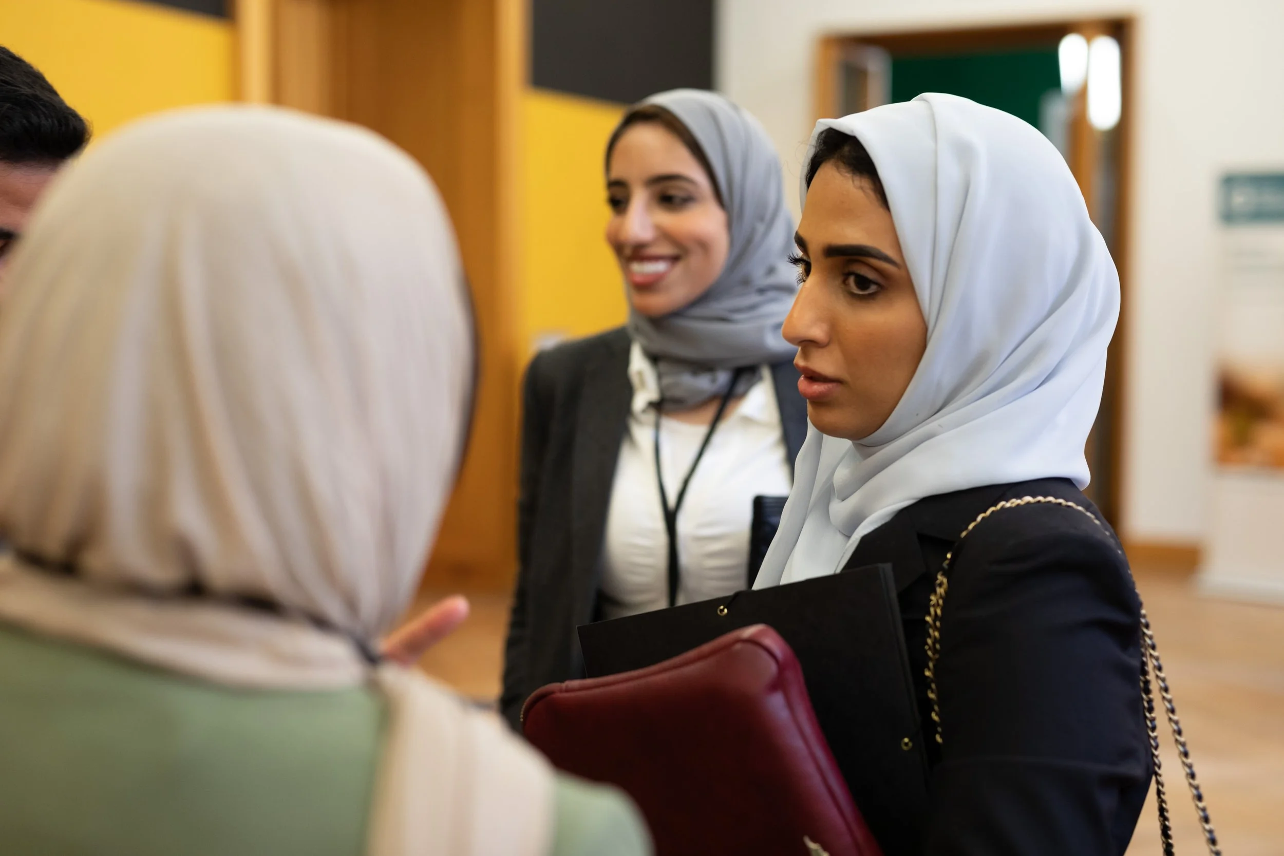 Zwei Frauen in Bekleidung mit Kopftüchern sprechen in einem Raum mit bunten Wänden.