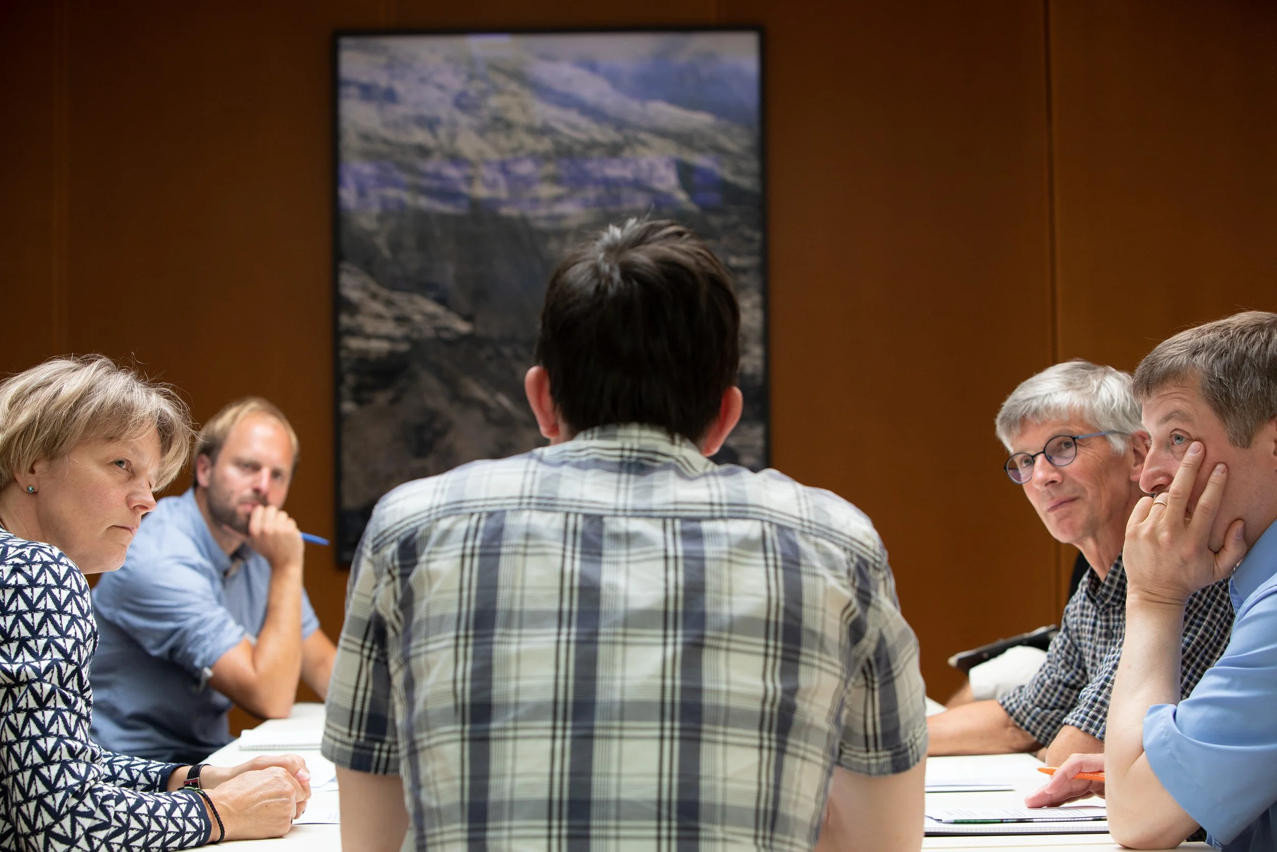 Gruppe von Menschen in einer Besprechung, die um einen Tisch sitzen und diskutieren.