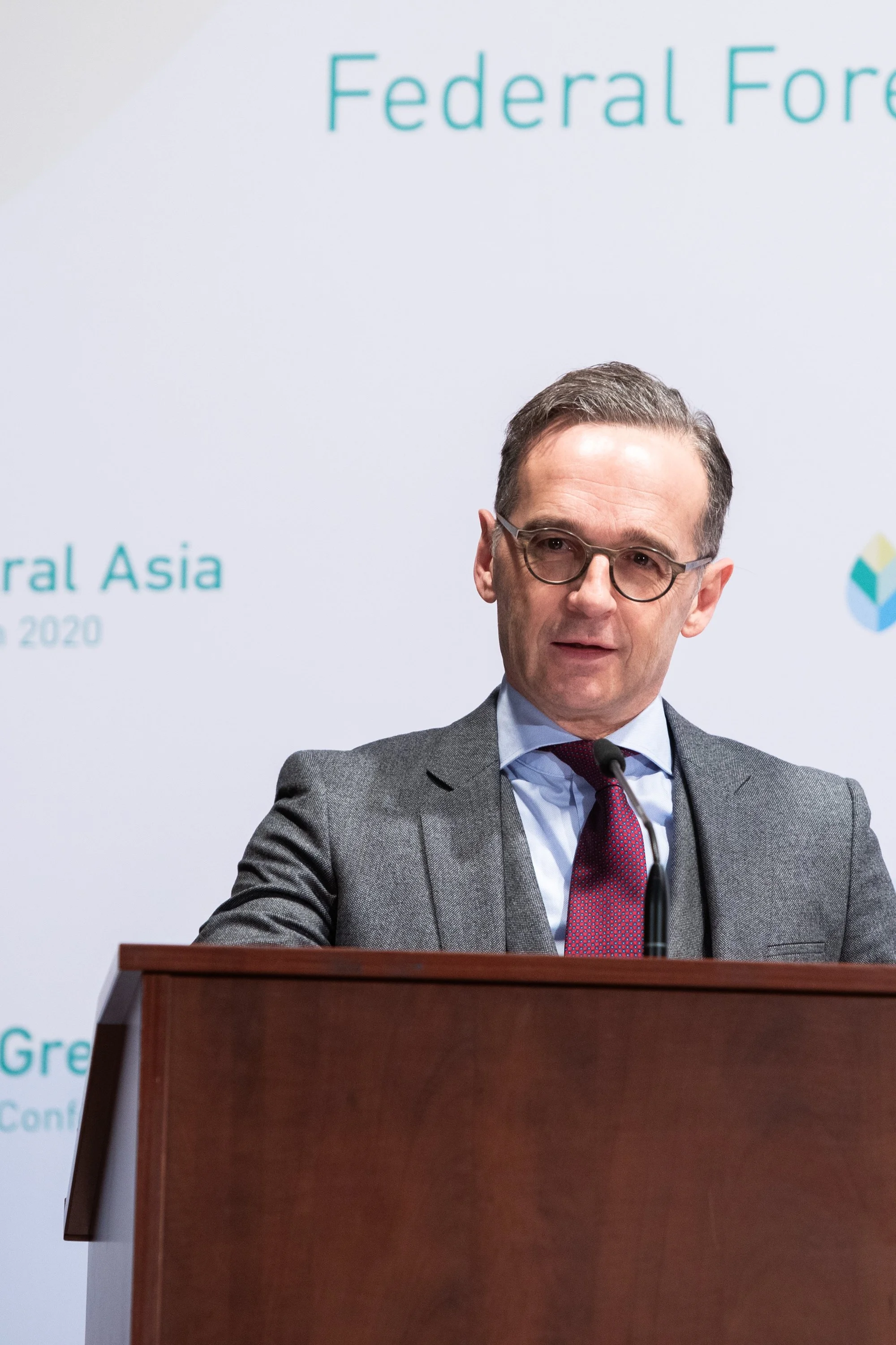 Außenminister Heiko Maas steht an einem Rednerpult und spricht bei einer Konferenz, im Hintergrund sind Wörter wie 'Federal', 'Asia' und '2020' sichtbar.