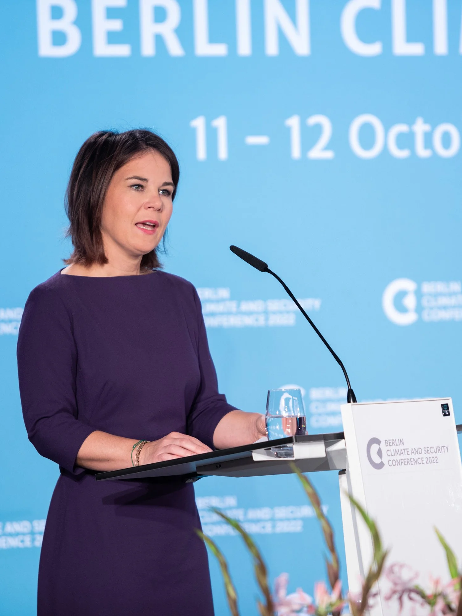 Außenministerin Annalena Baerbock spricht bei der Berlin-Climate-Security-Konferenz am Rednerpult, im Hintergrund eine Projektionswand mit Text zur Berliner Klimakonferenz 2022.