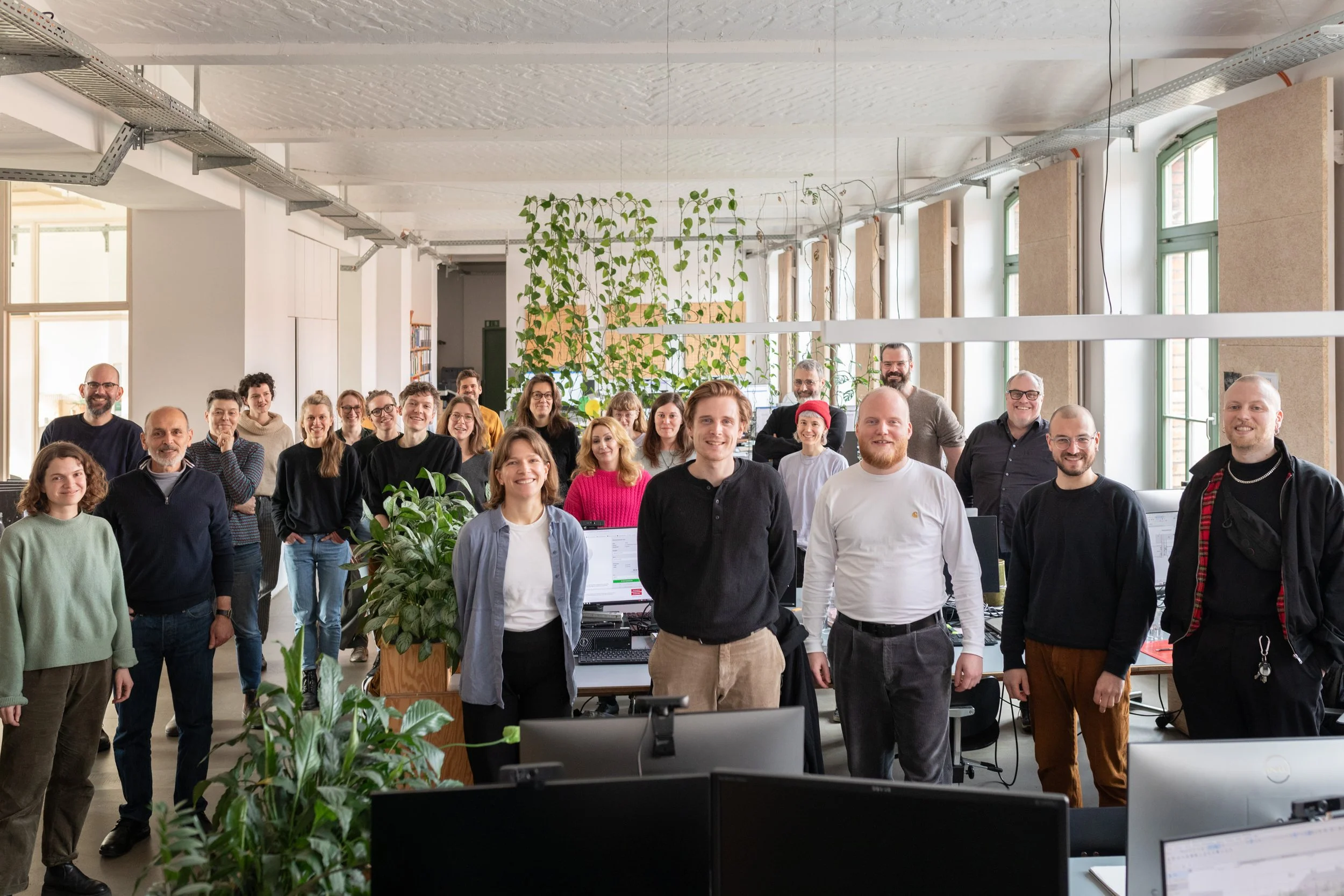 Gruppe von Menschen in einem Büro, die vor einem Computer posieren und lachen.