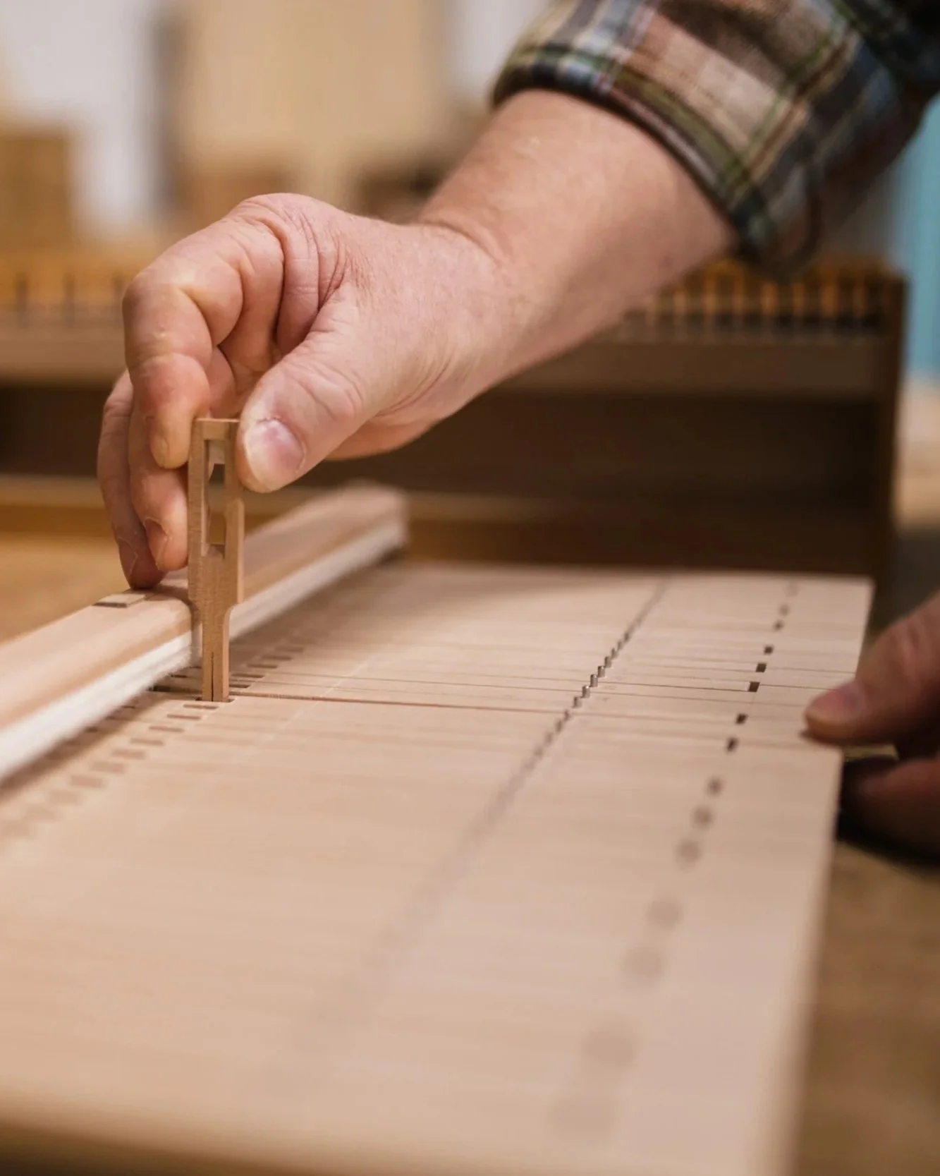 Hand, die an einem Klavichord die Saiten mit einem kleinen Holzstück berührt.