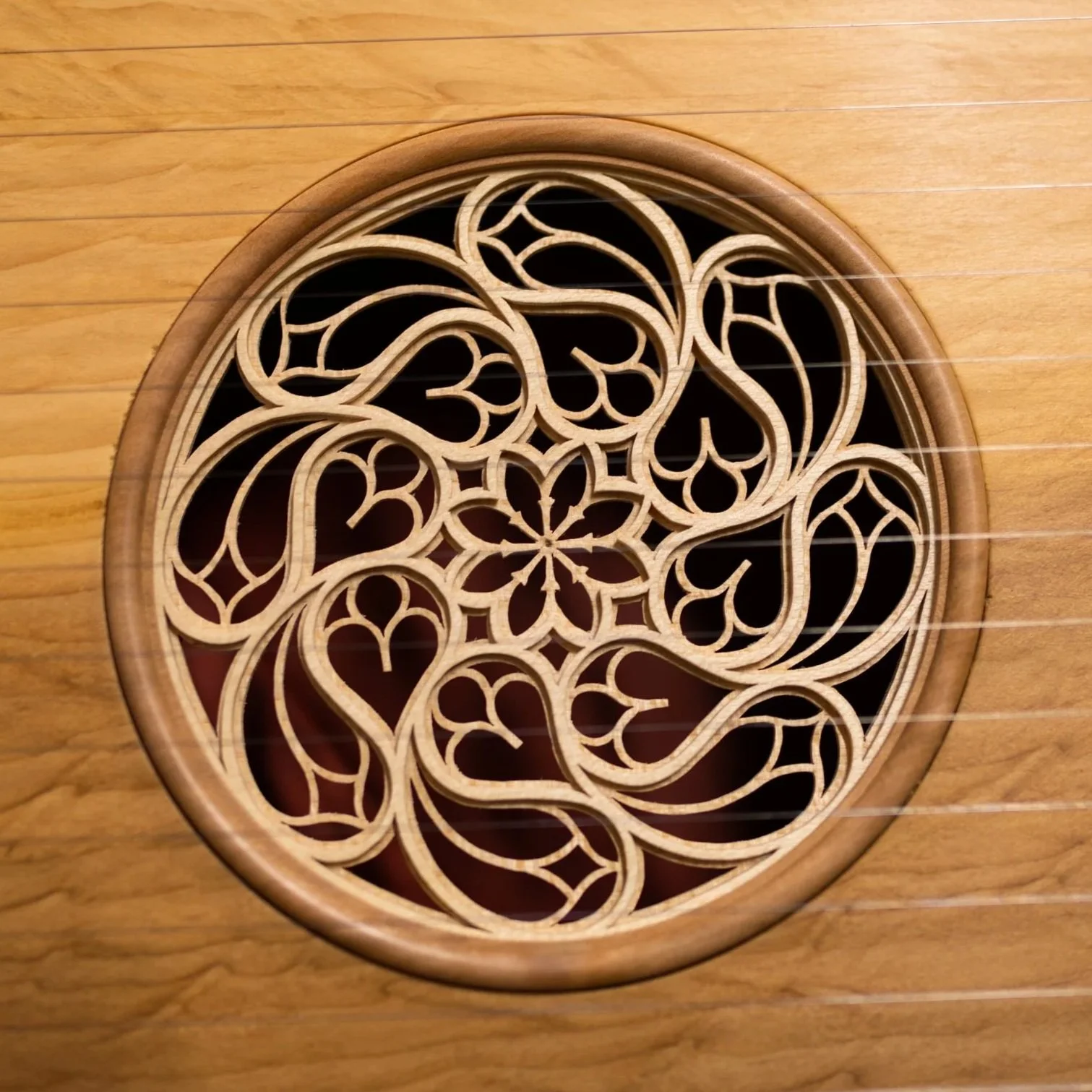 Ein rundes Holzornament mit floralen und geschwungenen Mustern, auf einem Holztisch platziert.