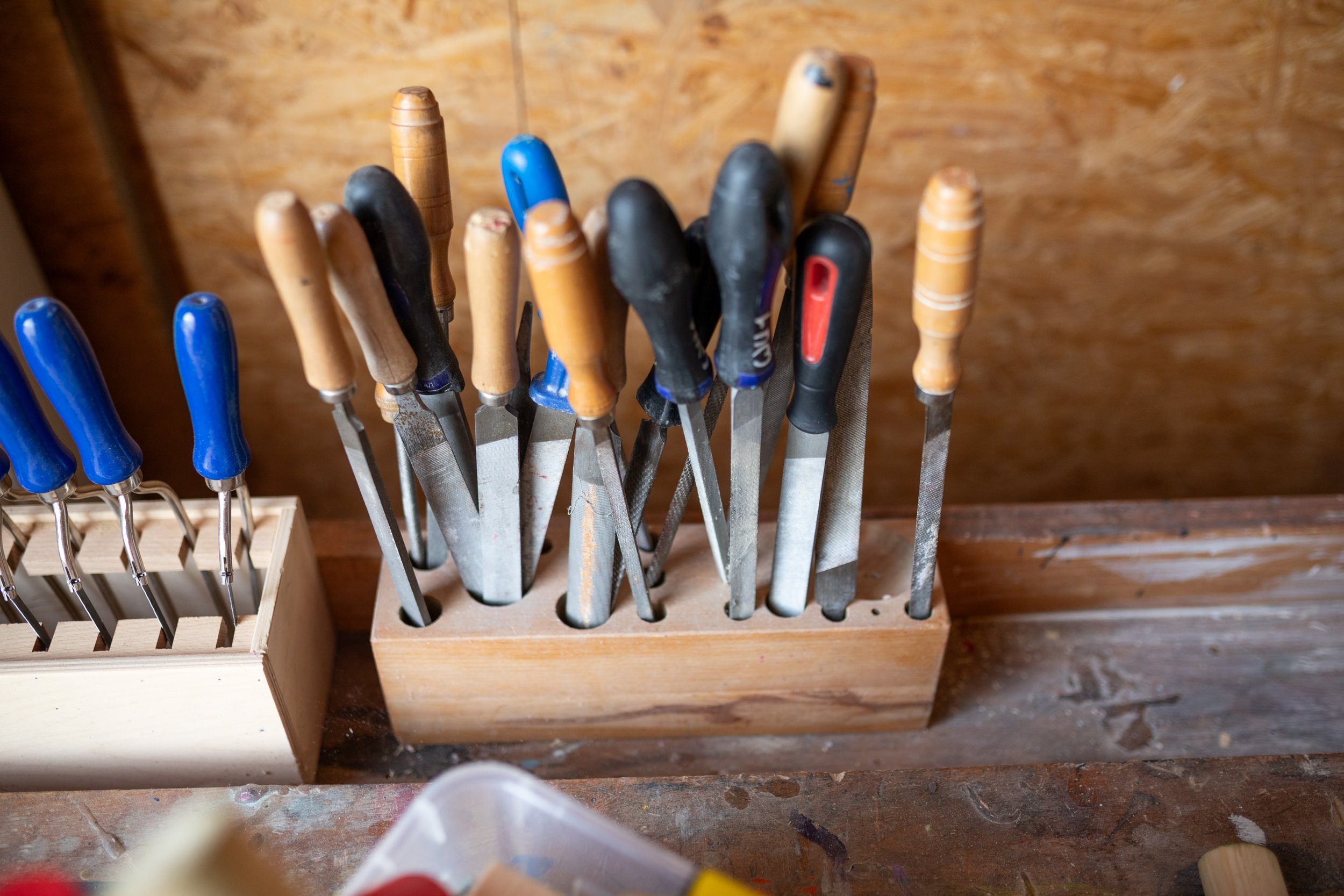 Verschiedene Holz- und Meißelwerkzeuge in einem Werkzeughalter aus Holz.