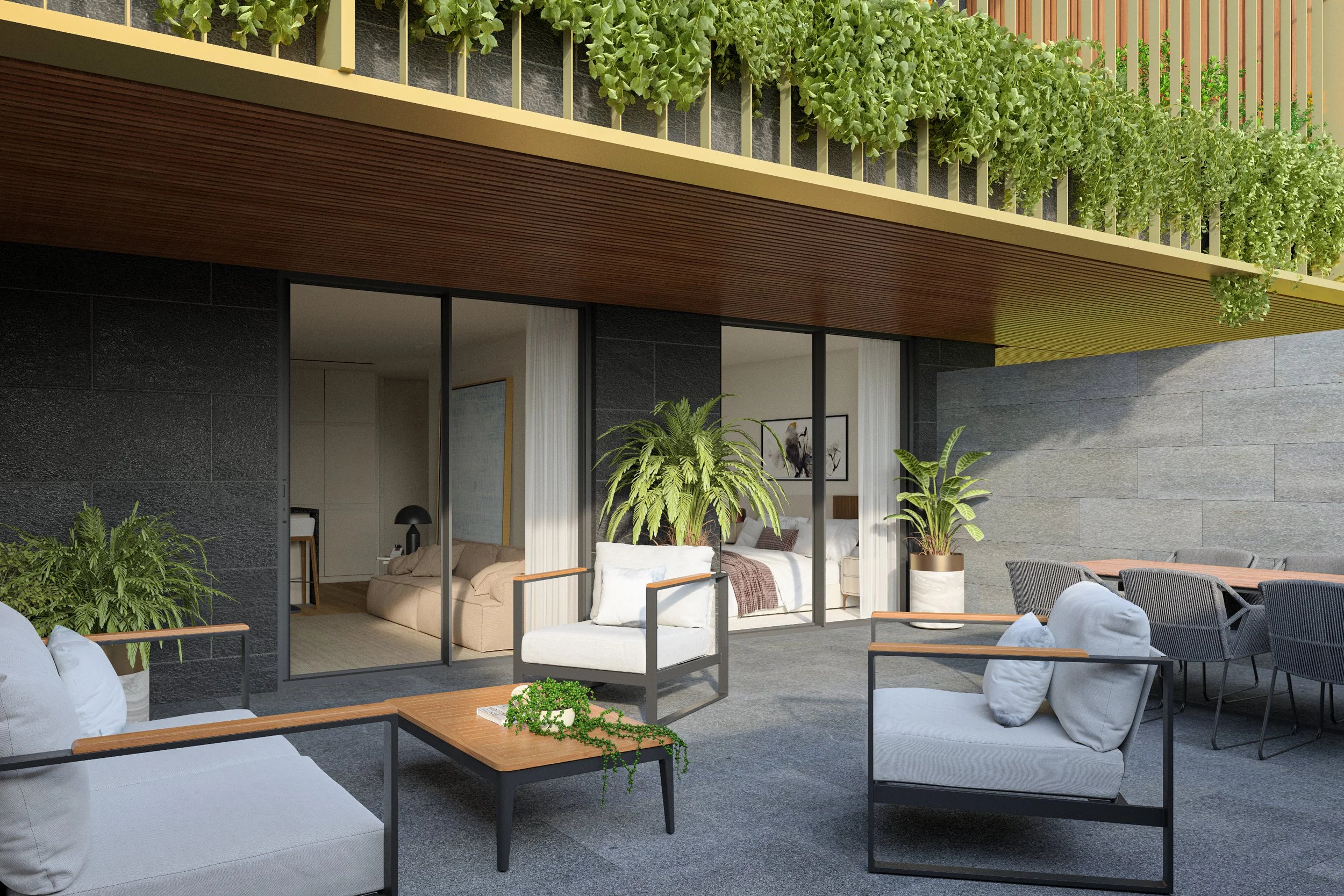 Modern outdoor patio with white cushioned seating, wooden tables, and potted plants, including green foliage on a balcony above and a view into the living room through large glass sliding doors.