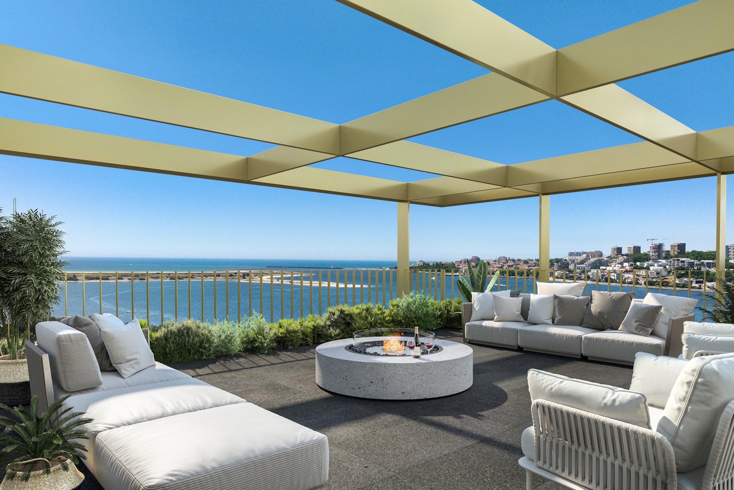 Outdoor rooftop lounge area with white cushioned chairs and sofas, a circular fire pit with a small fire, surrounded by greenery, overlooking a body of water and a city skyline under a clear blue sky, covered by a modern geometric pergola.